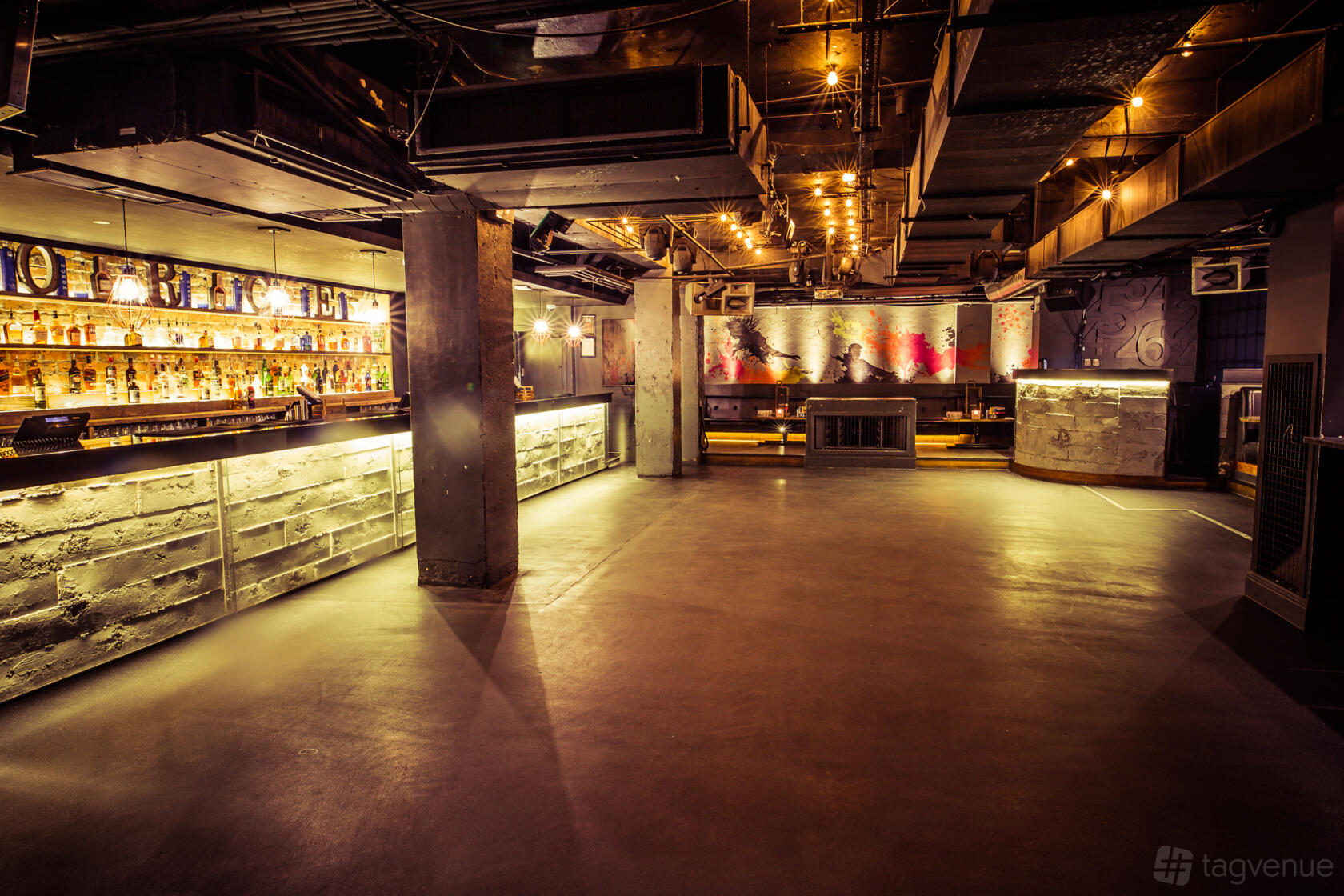 An event space with industrial pillars, illuminated bar counters, and ambient ceiling lights at Forge.