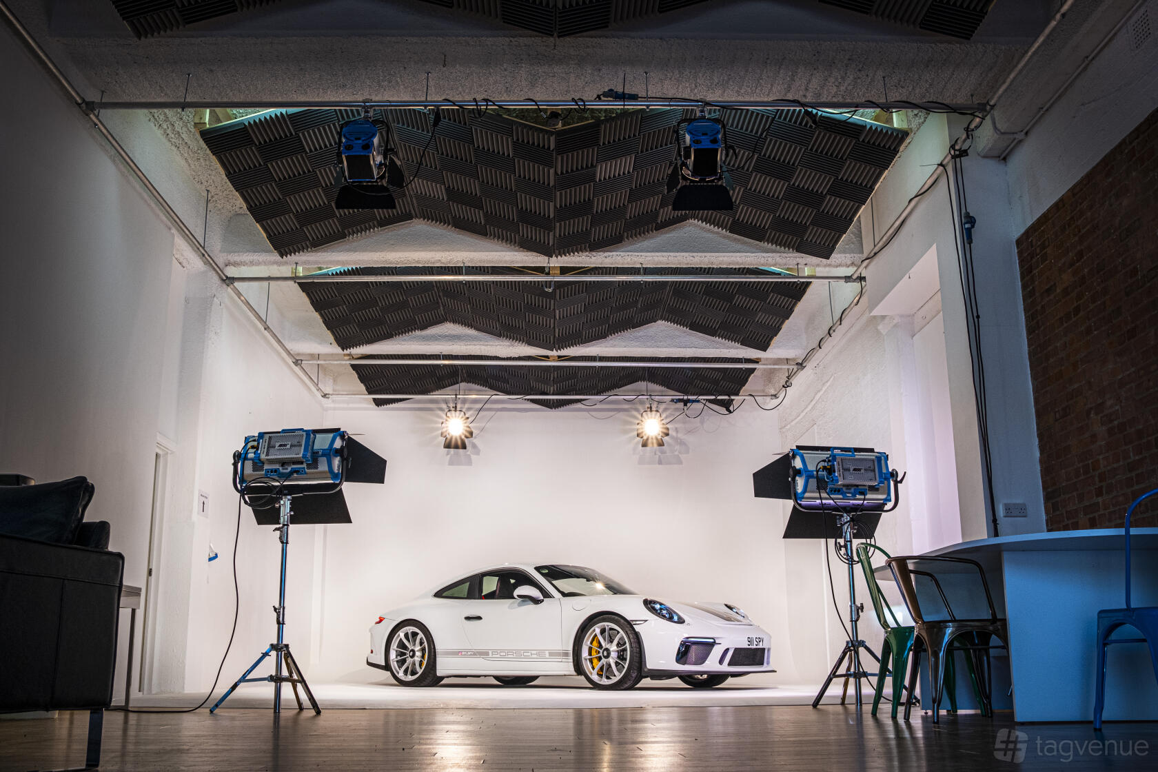 A photo studio with a white cyclorama wall, professional lighting rigs, and a sports car at Tower Bridge Studios.