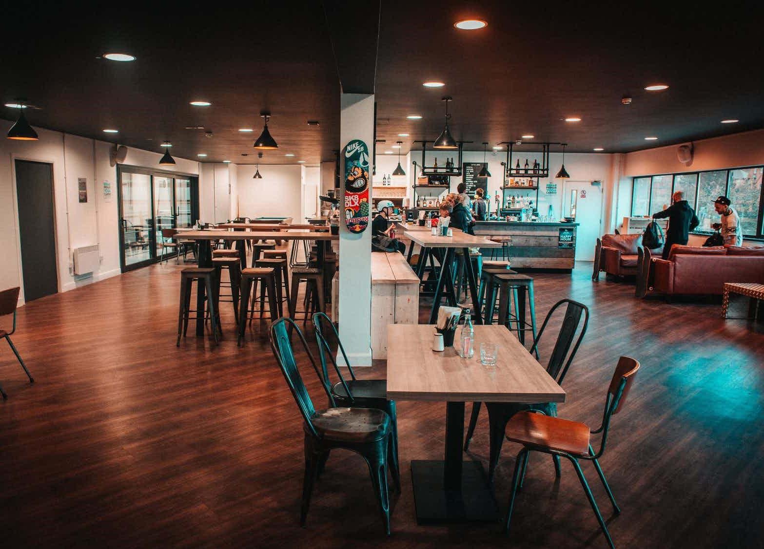 A restaurant with wooden floors, metal chairs, high tables, and a bar counter at The View Bar and Restaurant.