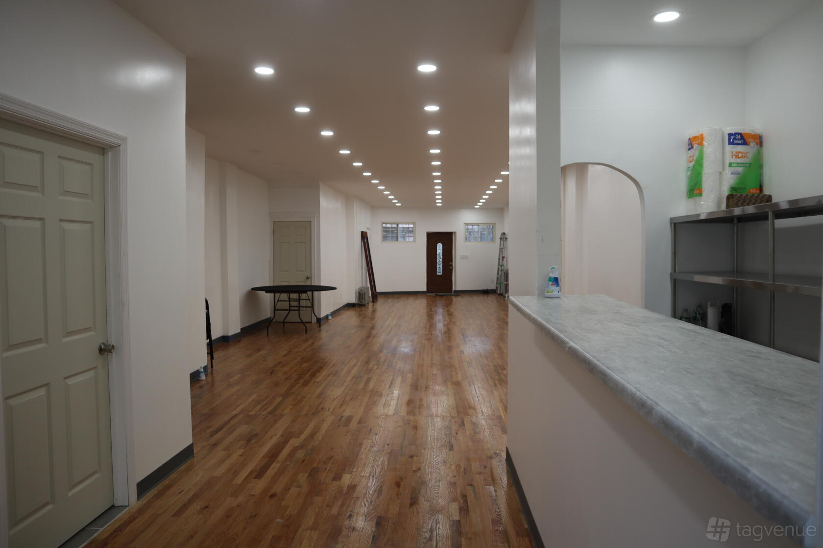 An event venue with polished wooden floors, white walls, and recessed ceiling lights at The Graham Space - Brooklyn.
