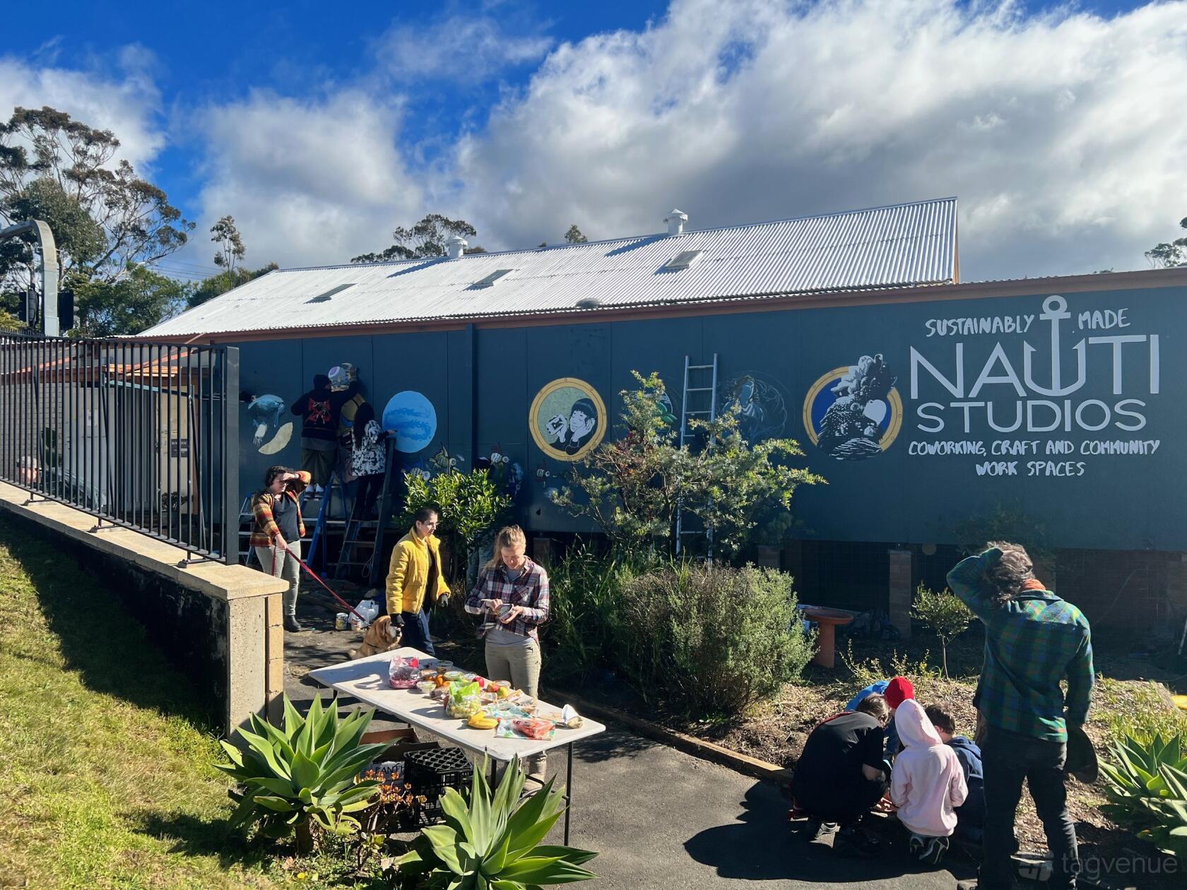 An office building exterior with large mural artwork and people gathered outside at Nauti Studios.