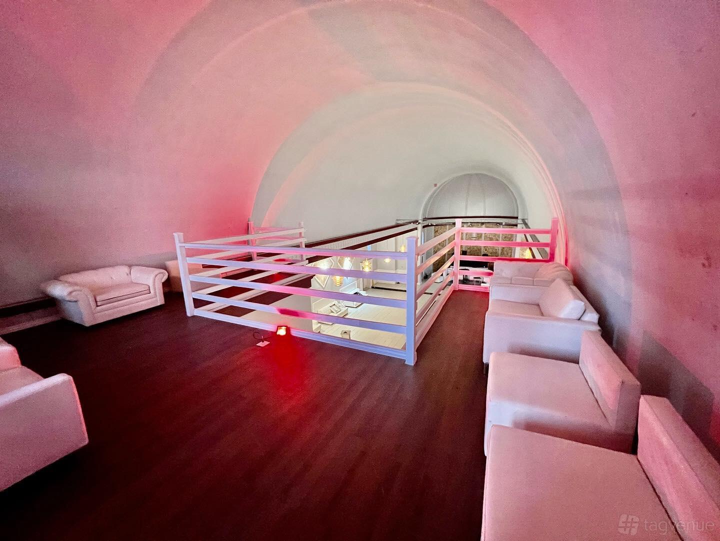 A hall with arched white ceilings, white sofas, and a wooden floor on the mezzanine at The Victorian Banquet Hall.