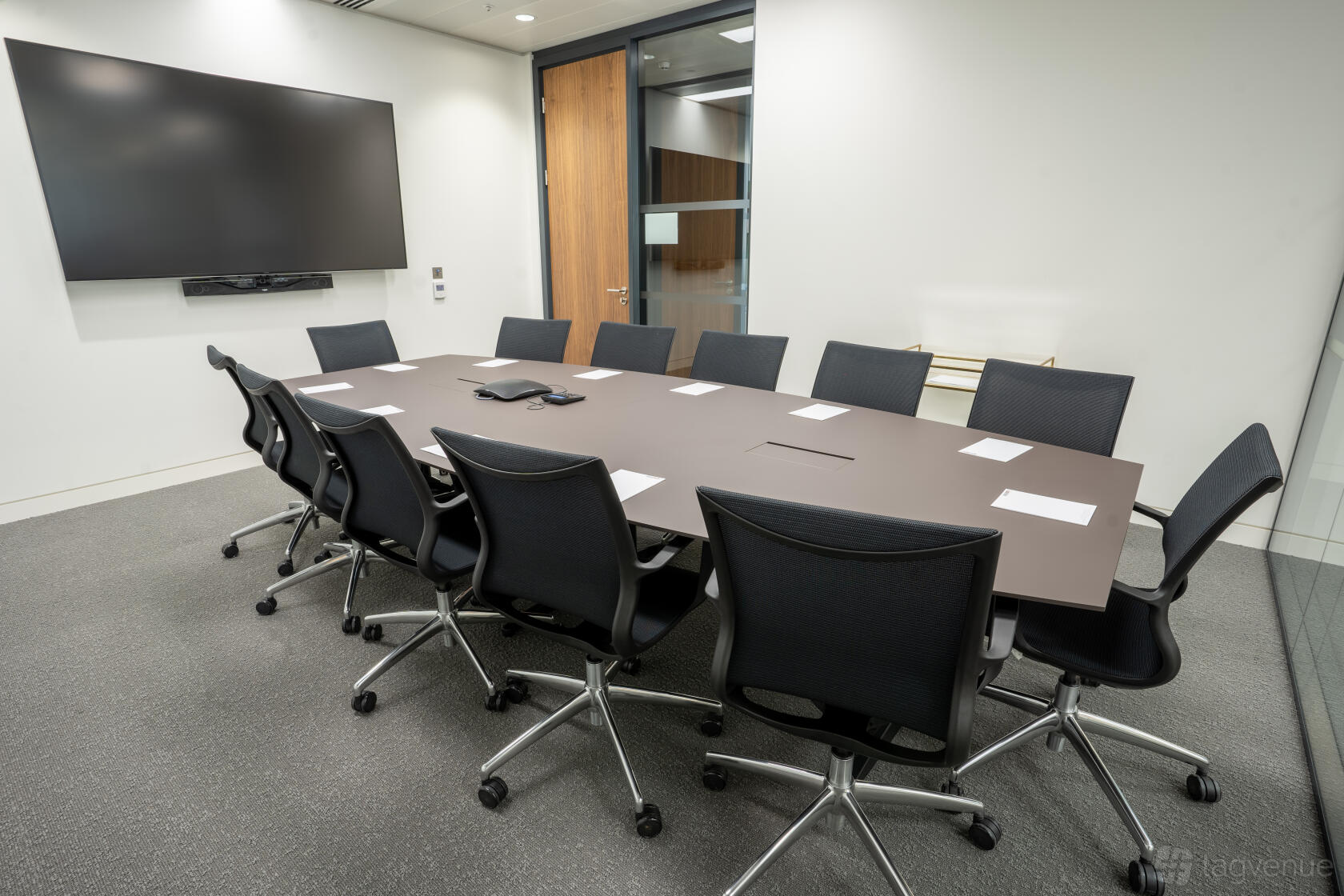 A meeting room with a long table, black swivel chairs, and a wall-mounted flat screen at London Conference Centre.