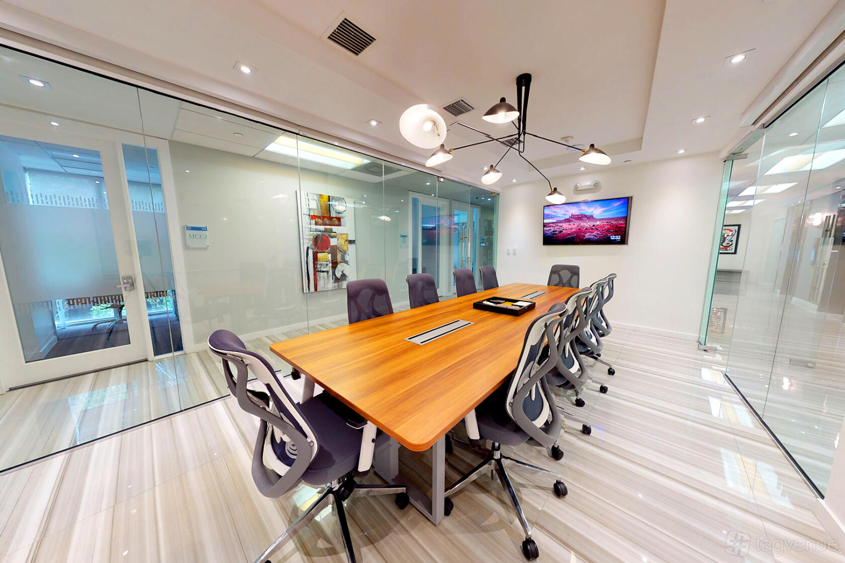 A meeting room with a long wooden table, ergonomic chairs, and glass walls at ICONIC WORKSPACES DOWNTOWN MIAMI.