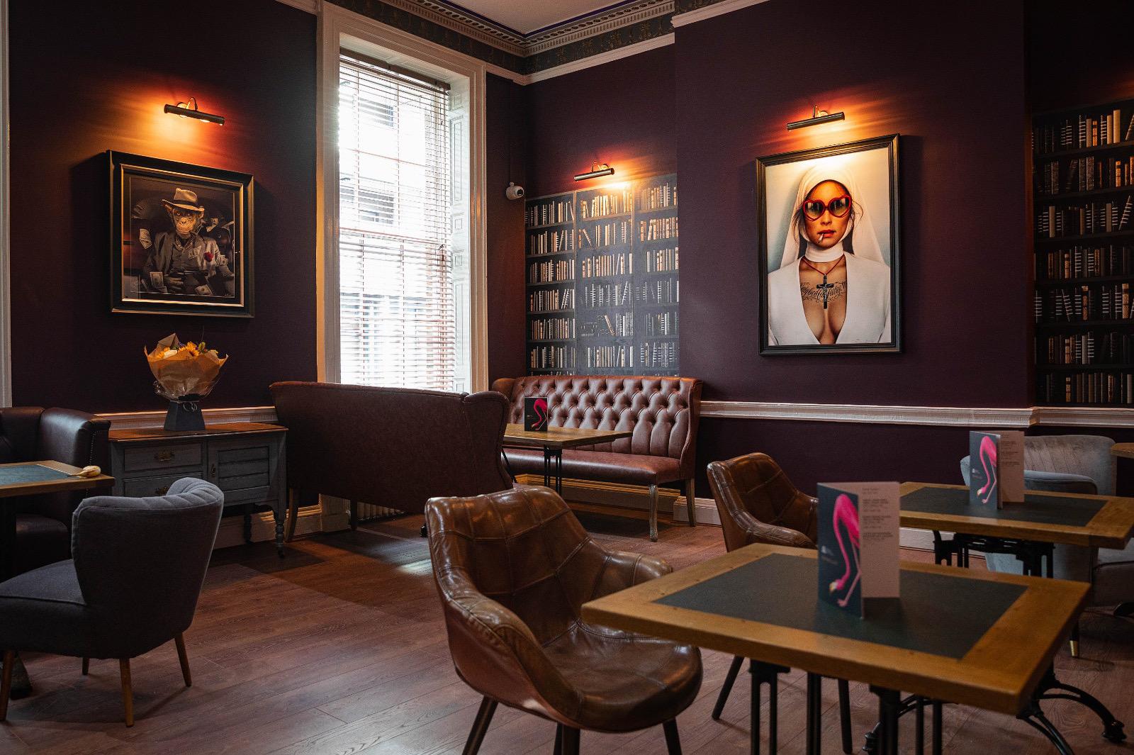 A function room in a cocktail bar with leather armchairs, large windows, and book-lined walls at Royal Institution Bar.
