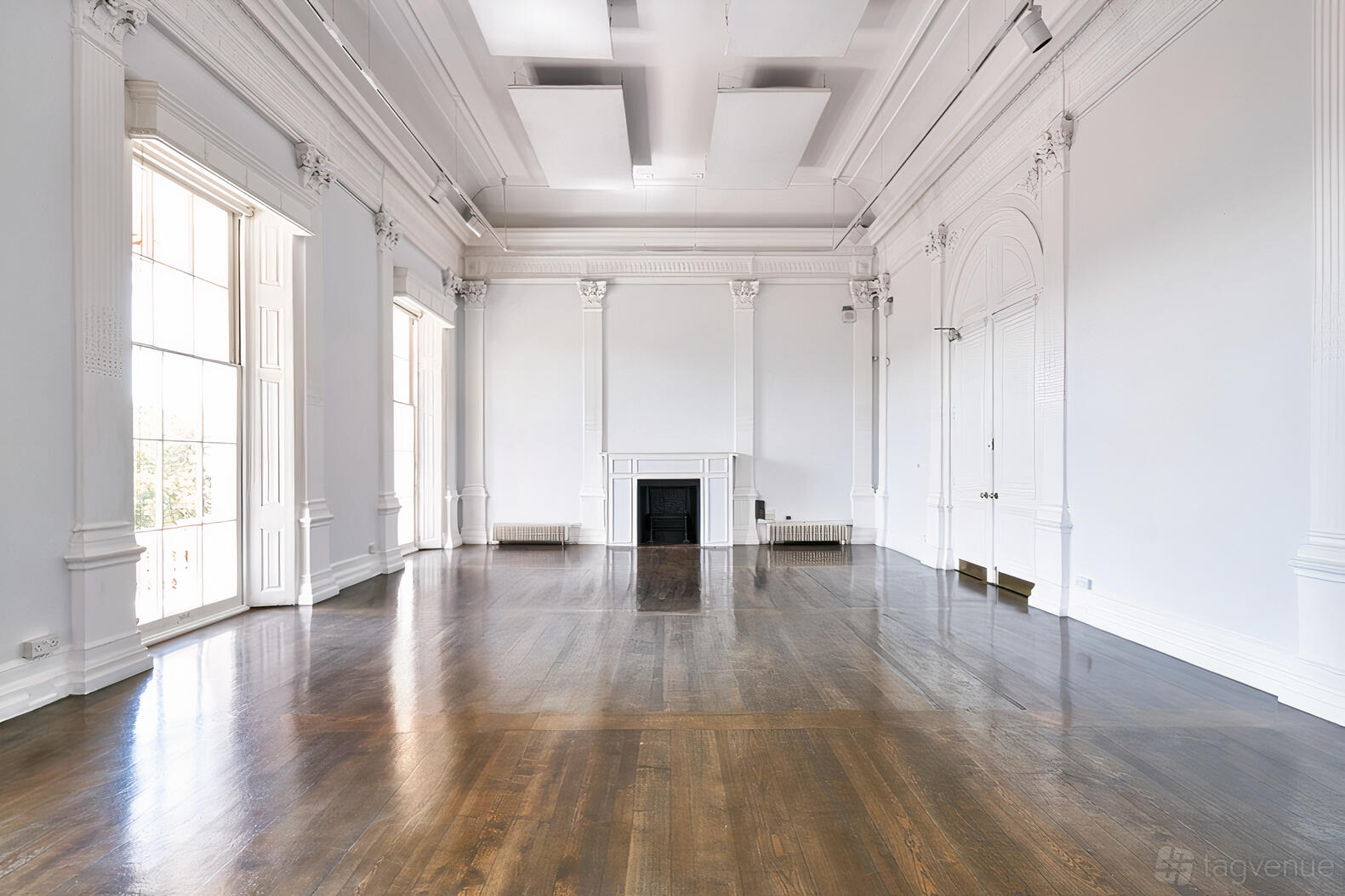 An event space in a gallery with tall windows, ornate white molding, and a decorative fireplace at Institute of Contemporary Arts.