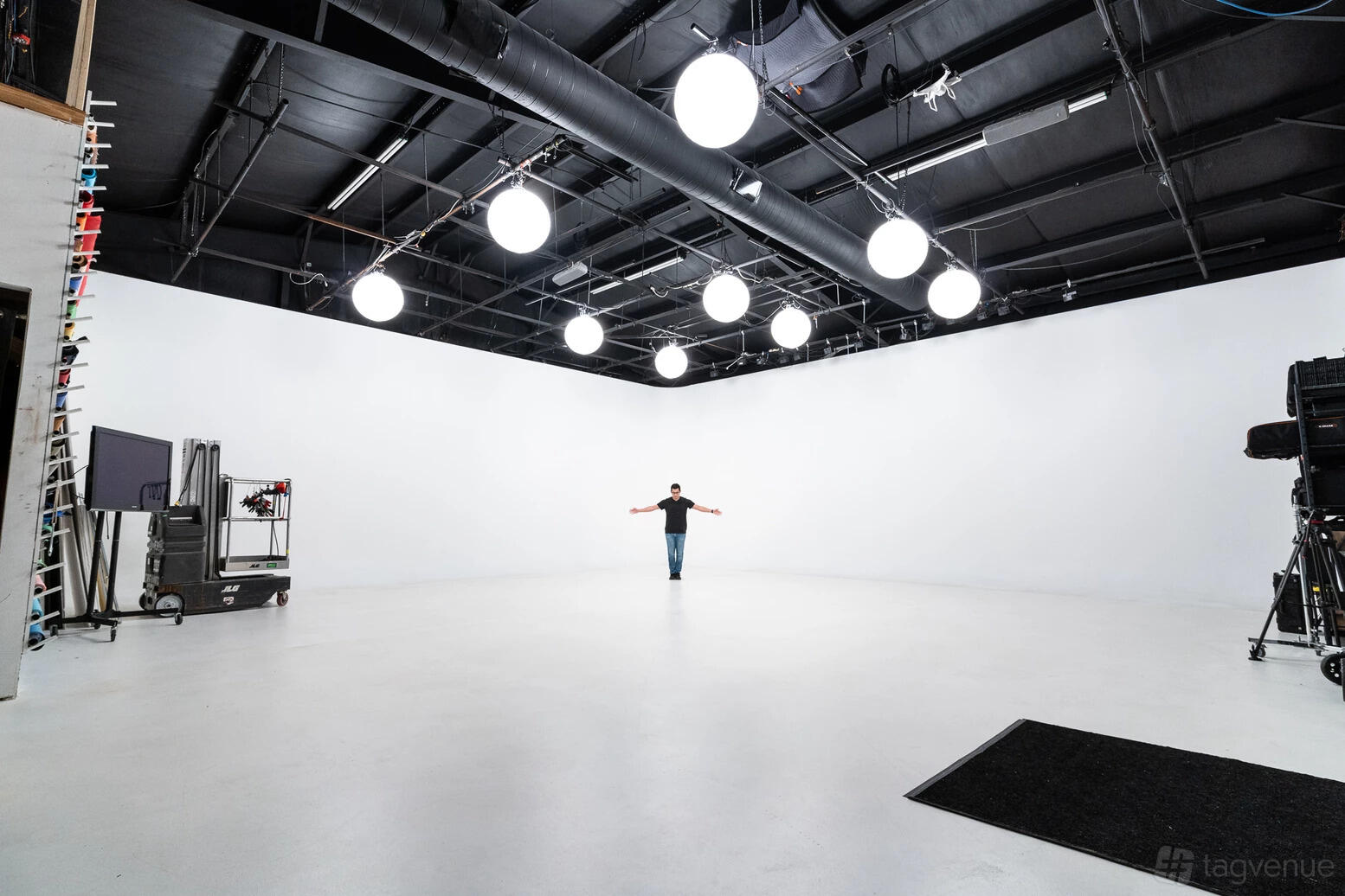 A photo studio with a seamless white cyclorama wall, high ceilings, and overhead globe lights at Northline Studios.