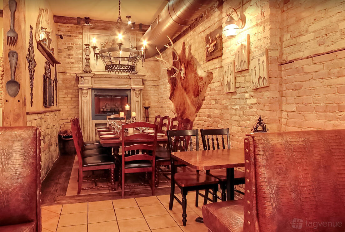 A restaurant dining room with exposed brick walls, antler decor, and a long wooden table set for guests at Staropolska Restaurant.