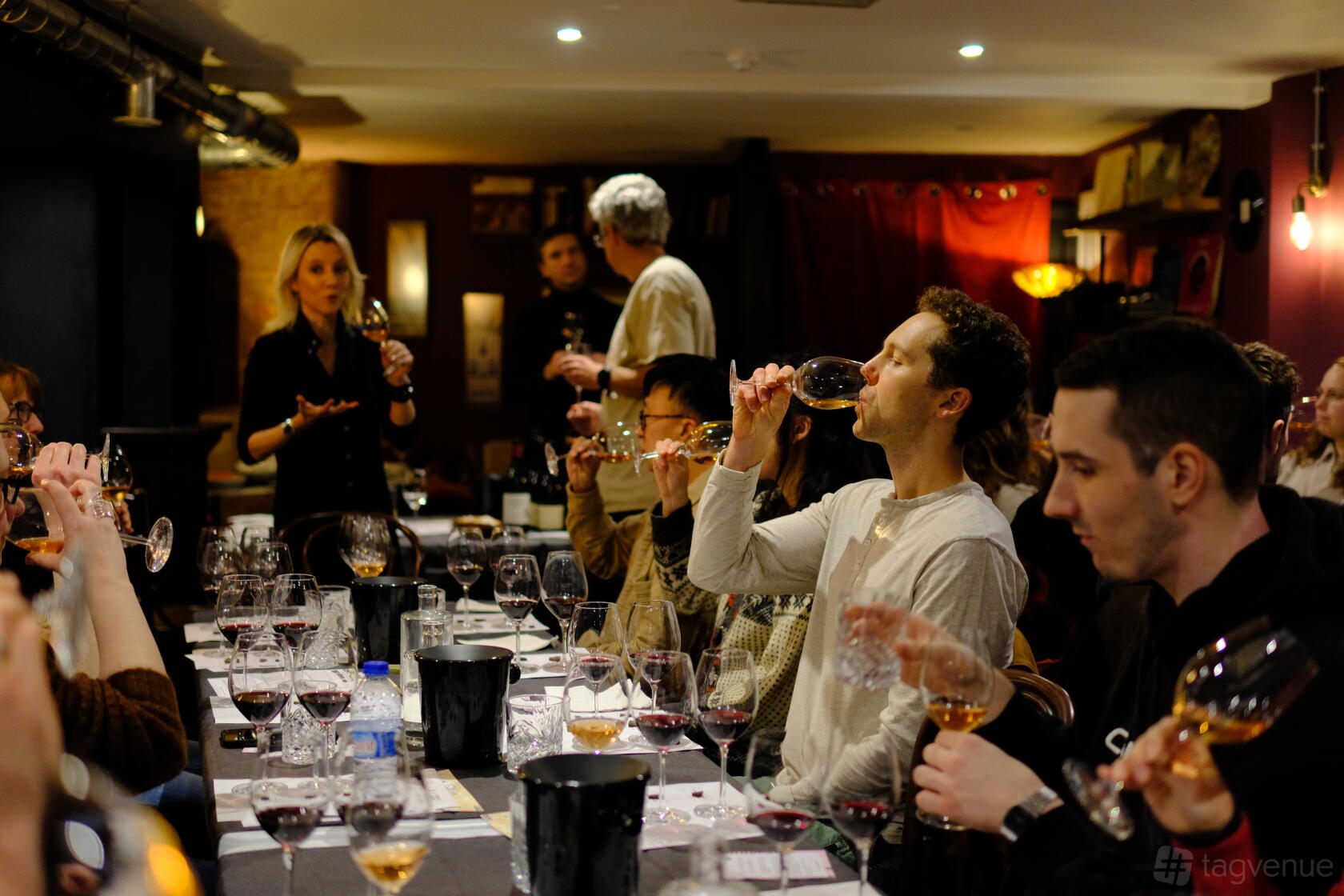 A cafe lounge with groups seated at long tables, wine glasses and dim ambient lighting at Fidelio.