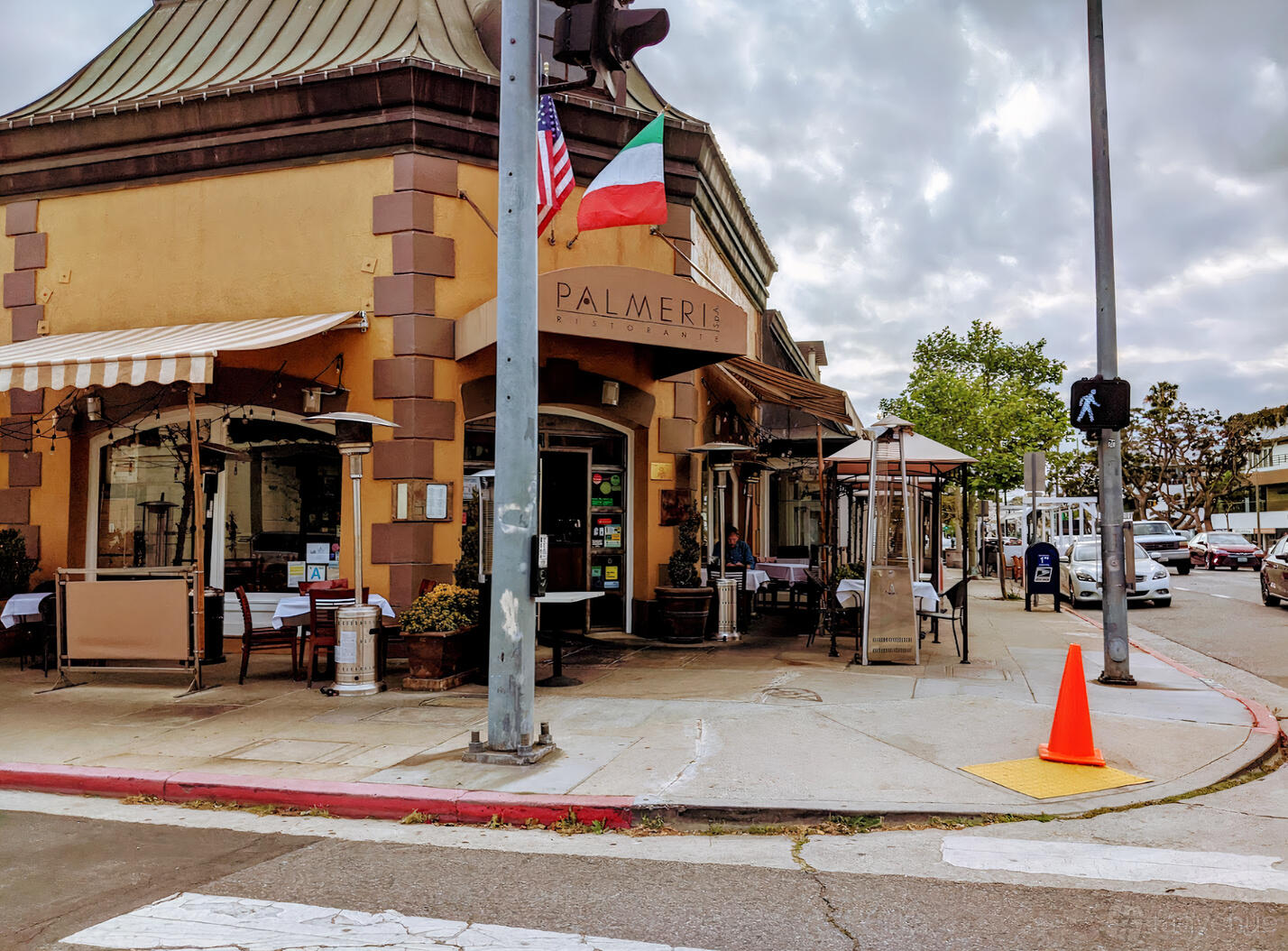 A restaurant with outdoor patio seating under striped awnings and international flags at Palmeri Ristorante.