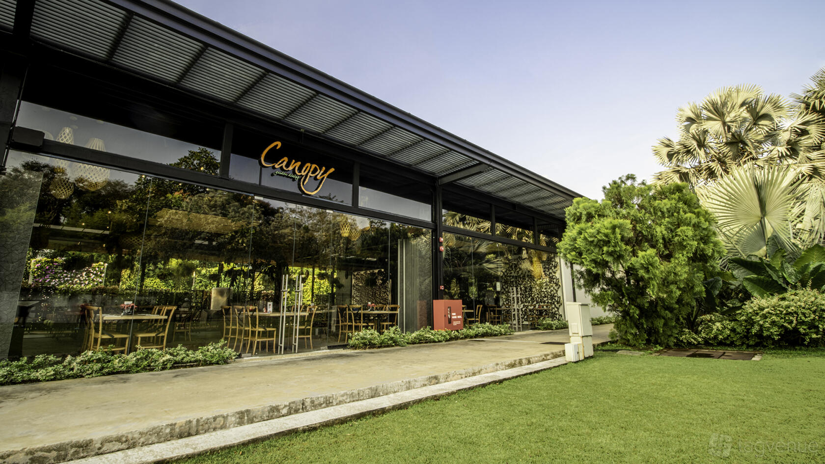 A restaurant with floor-to-ceiling glass walls, garden views, and outdoor seating at Canopy HortPark.