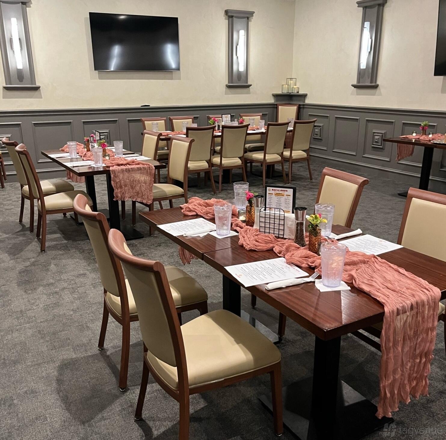 A dining room with wooden tables, cream upholstered chairs, and pink table runners at Max and Louie's New York Diner.