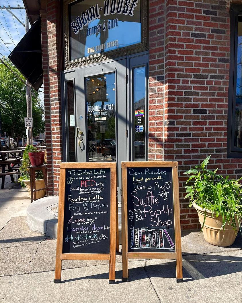 A café entrance with brick walls, glass doors, and sidewalk chalkboard menus at Social House.