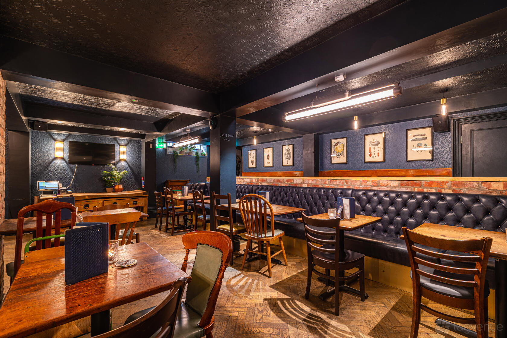 A pub dining room with tufted leather banquette seating, wooden tables, and framed artwork at The Bay Horse Tavern.