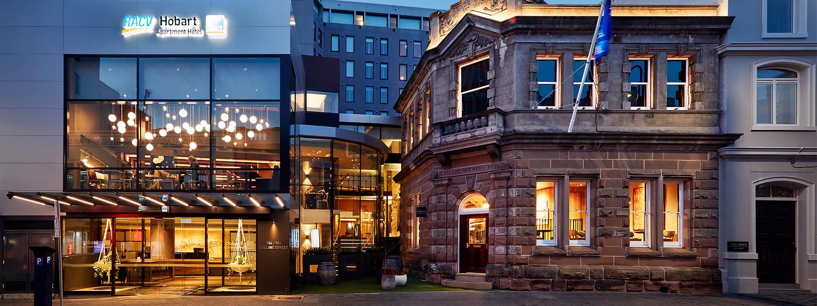 A hotel exterior with a blend of modern glass facade and historic stone architecture at RACV Hobart Hotel.