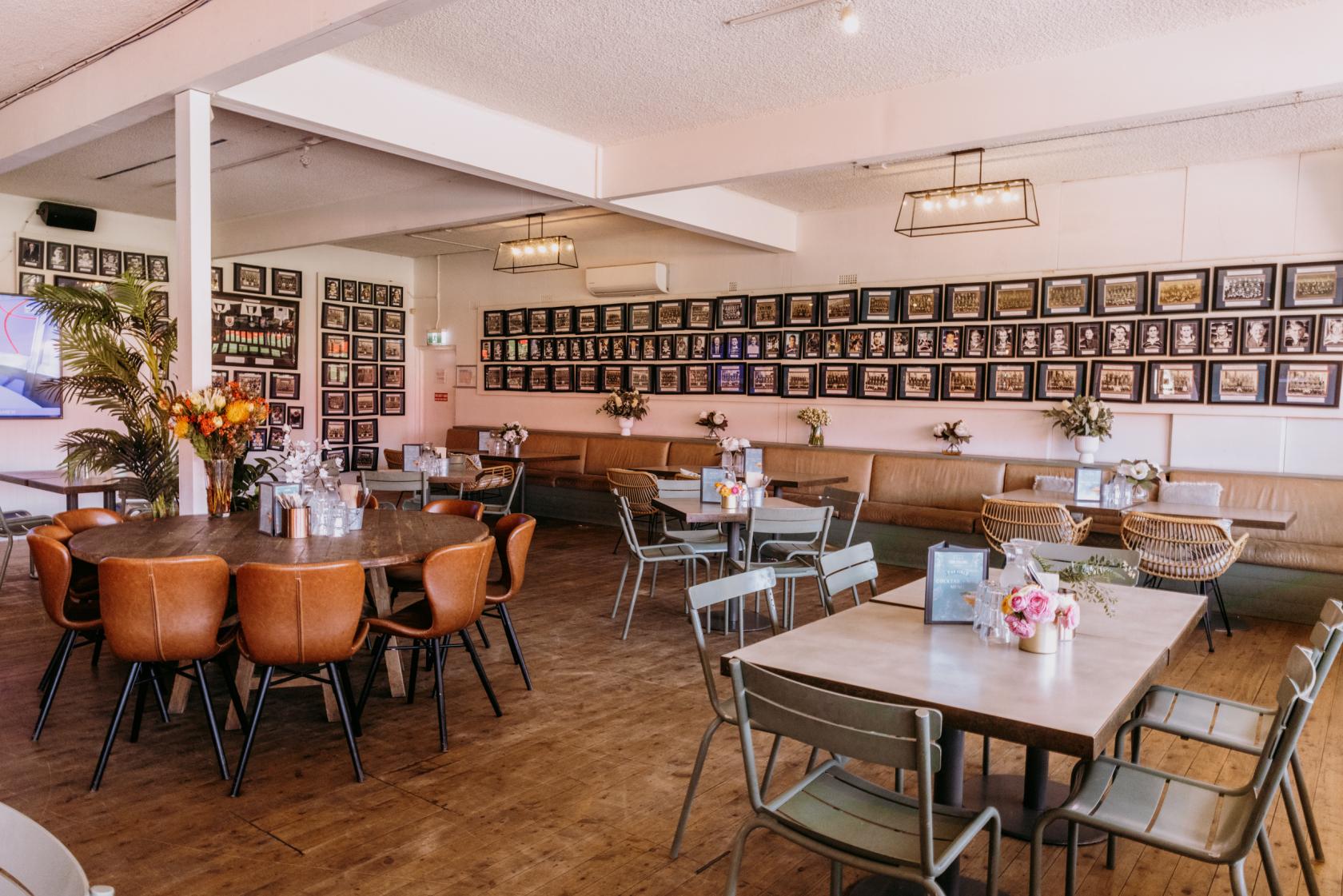 A function room with wood floors, framed photos on the walls, and mixed seating at The Field Bar.