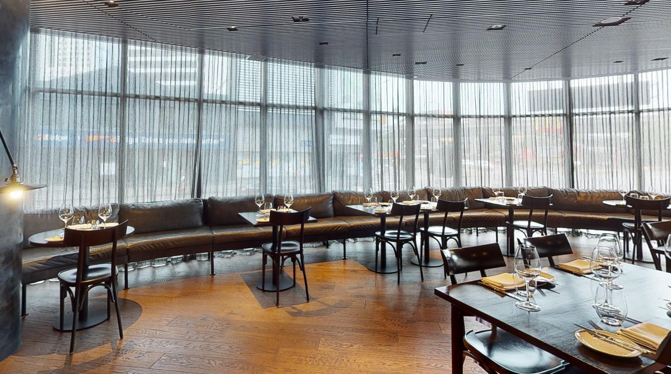 A hotel bar with floor-to-ceiling sheer curtains, curved banquette seating, and set tables at Shadow Play by Peppers.