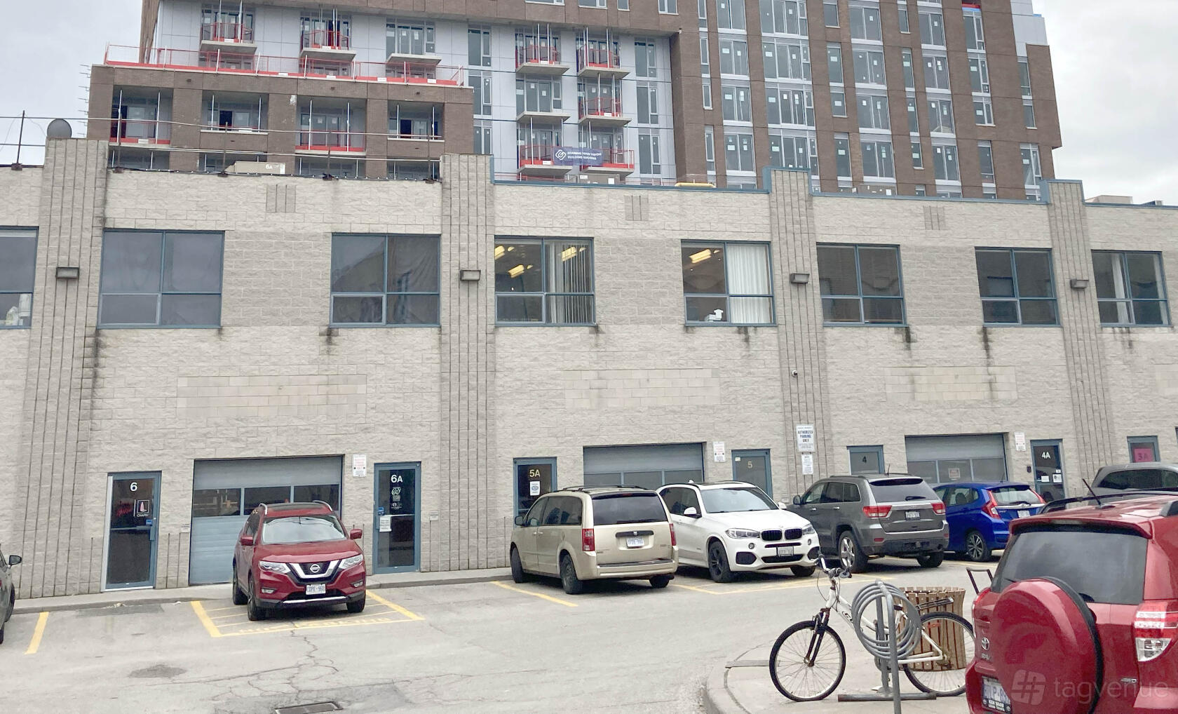 A film and photo studio with a beige brick exterior, large windows, and parking spaces at Studio Cozy.