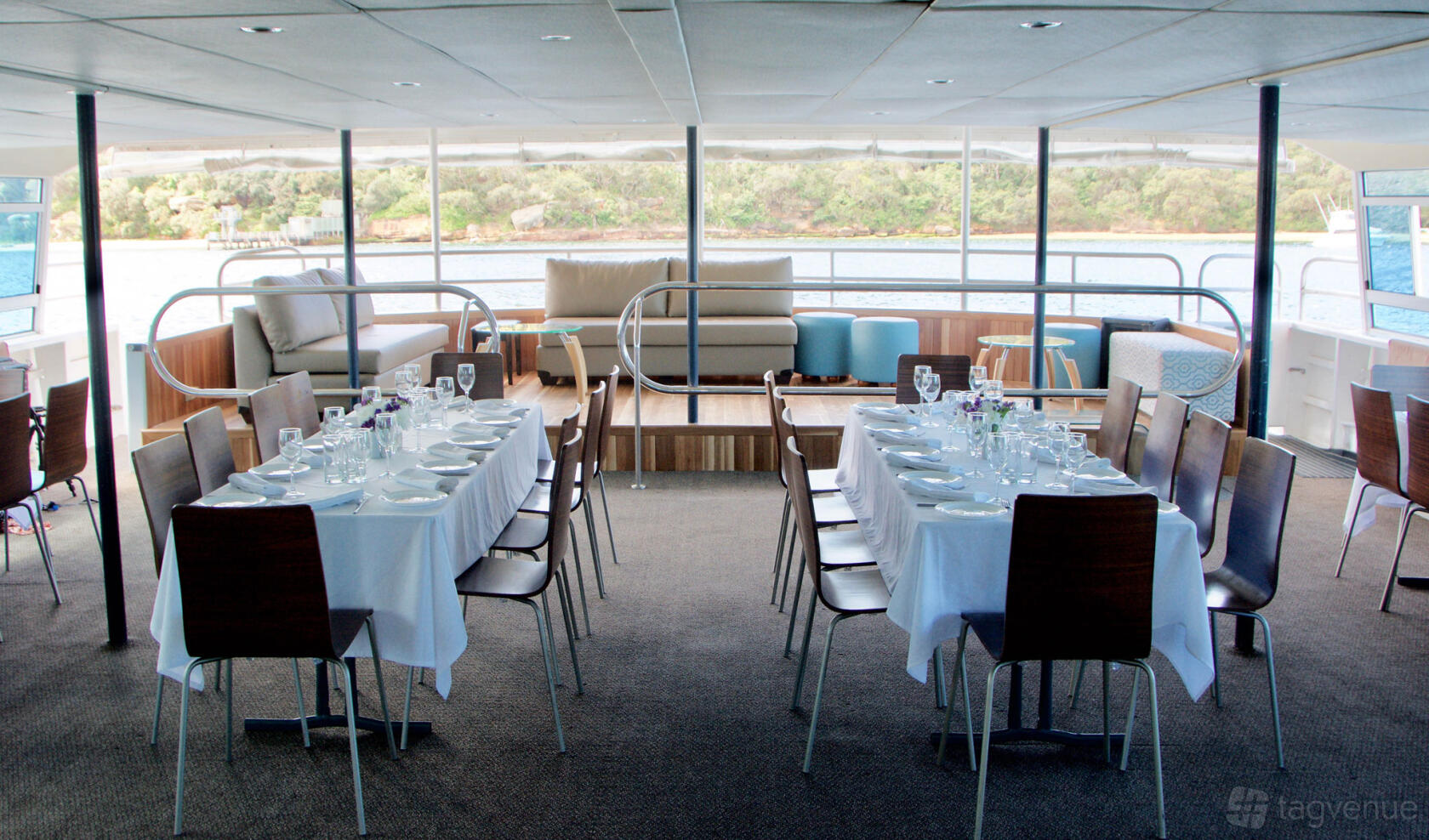 A boat venue with banquet tables set with white linens and glassware beside a lounge area at Eclipse.