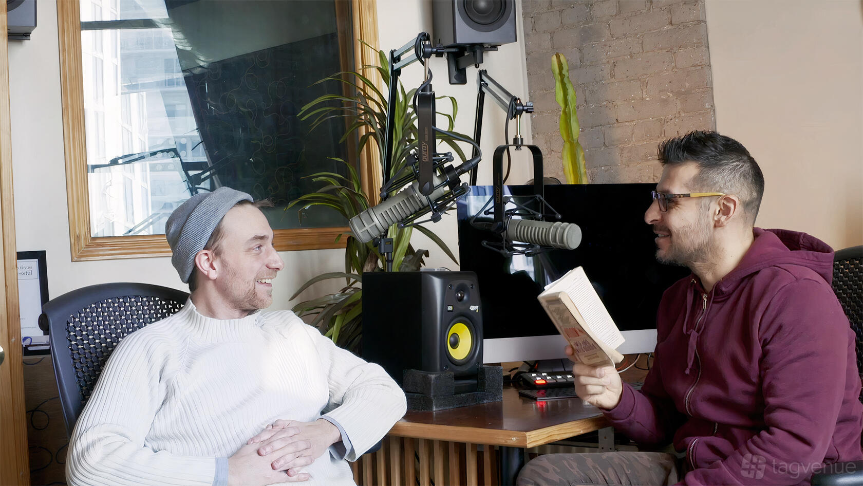 A photo and film studio with podcast microphones, a computer monitor, and exposed brick at RadioRadio Studio.