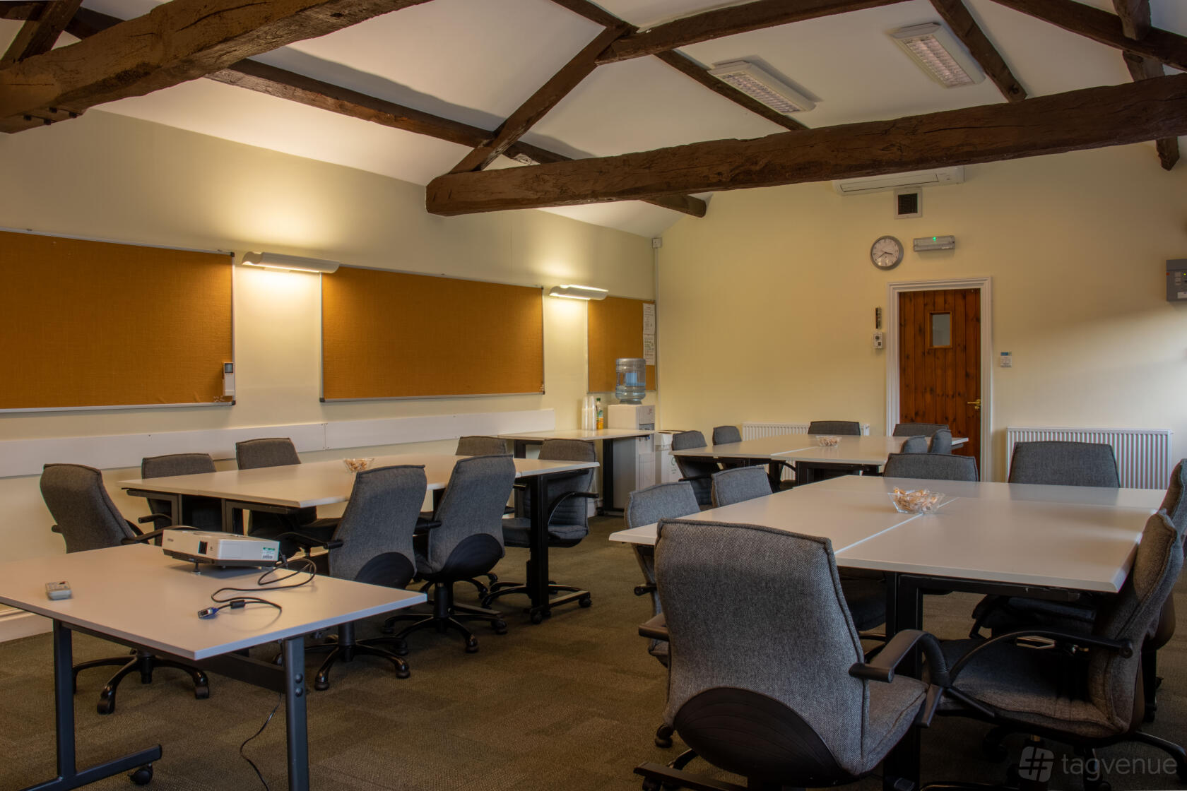 A country house meeting room with exposed wooden ceiling beams, grey chairs, and corkboards at Middle Aston House.