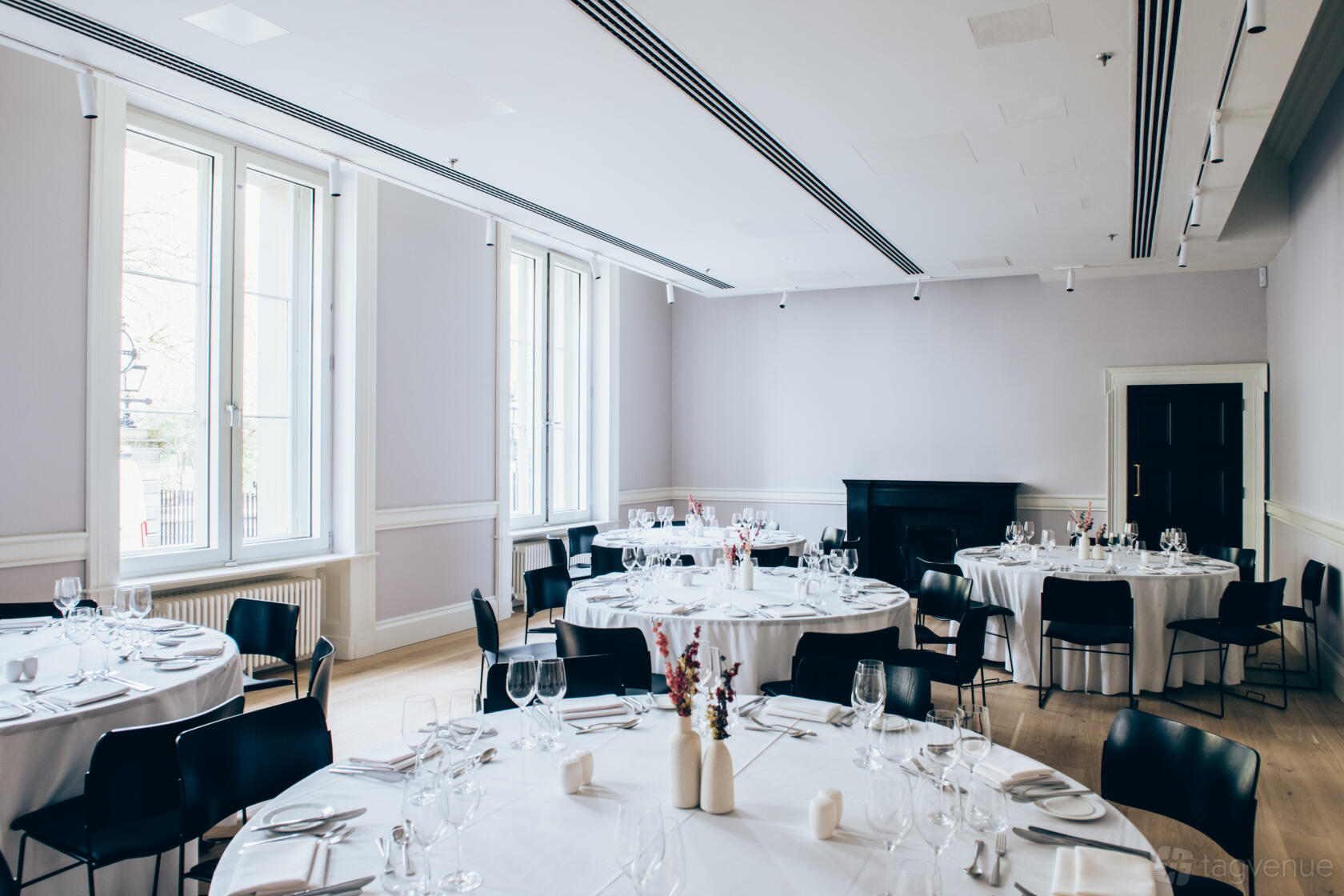 An event venue with large windows, round tables set with white linens, and natural light at The View.