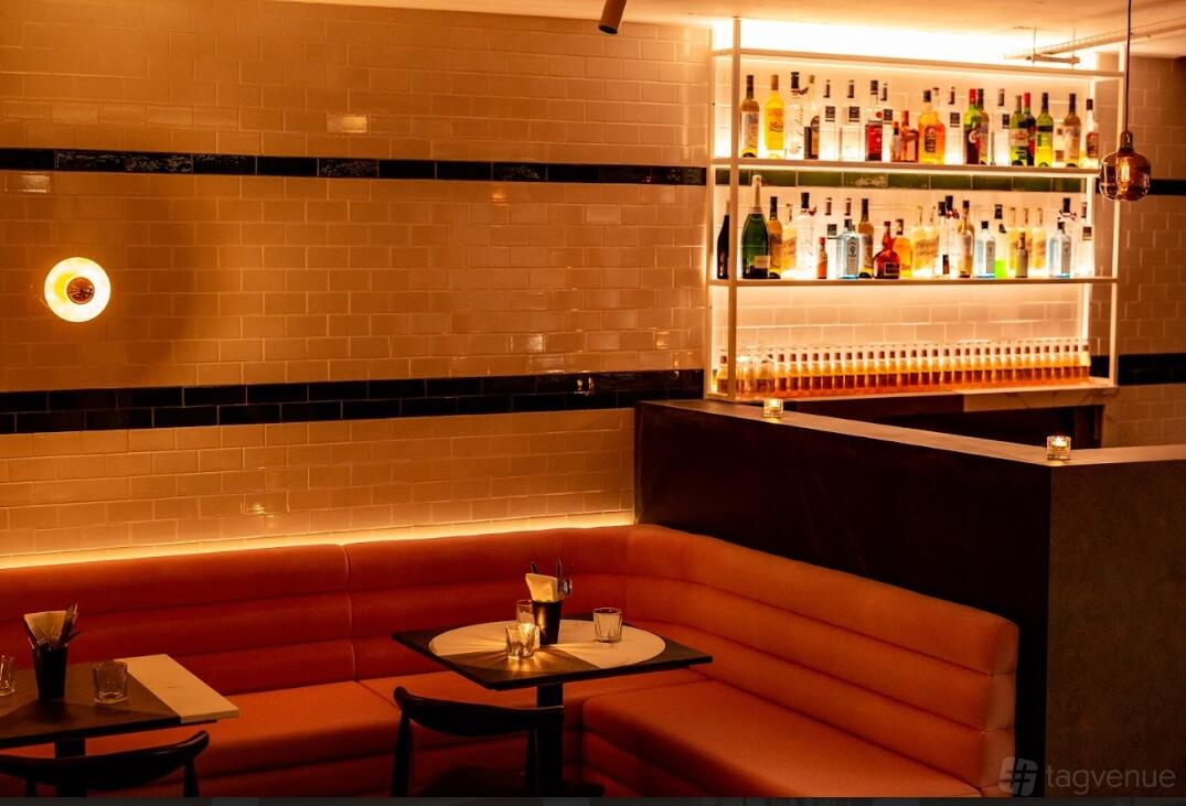 An event lounge with backlit shelves of spirits, peach banquette seating, and tiled walls at Le Bab Covent Garden.
