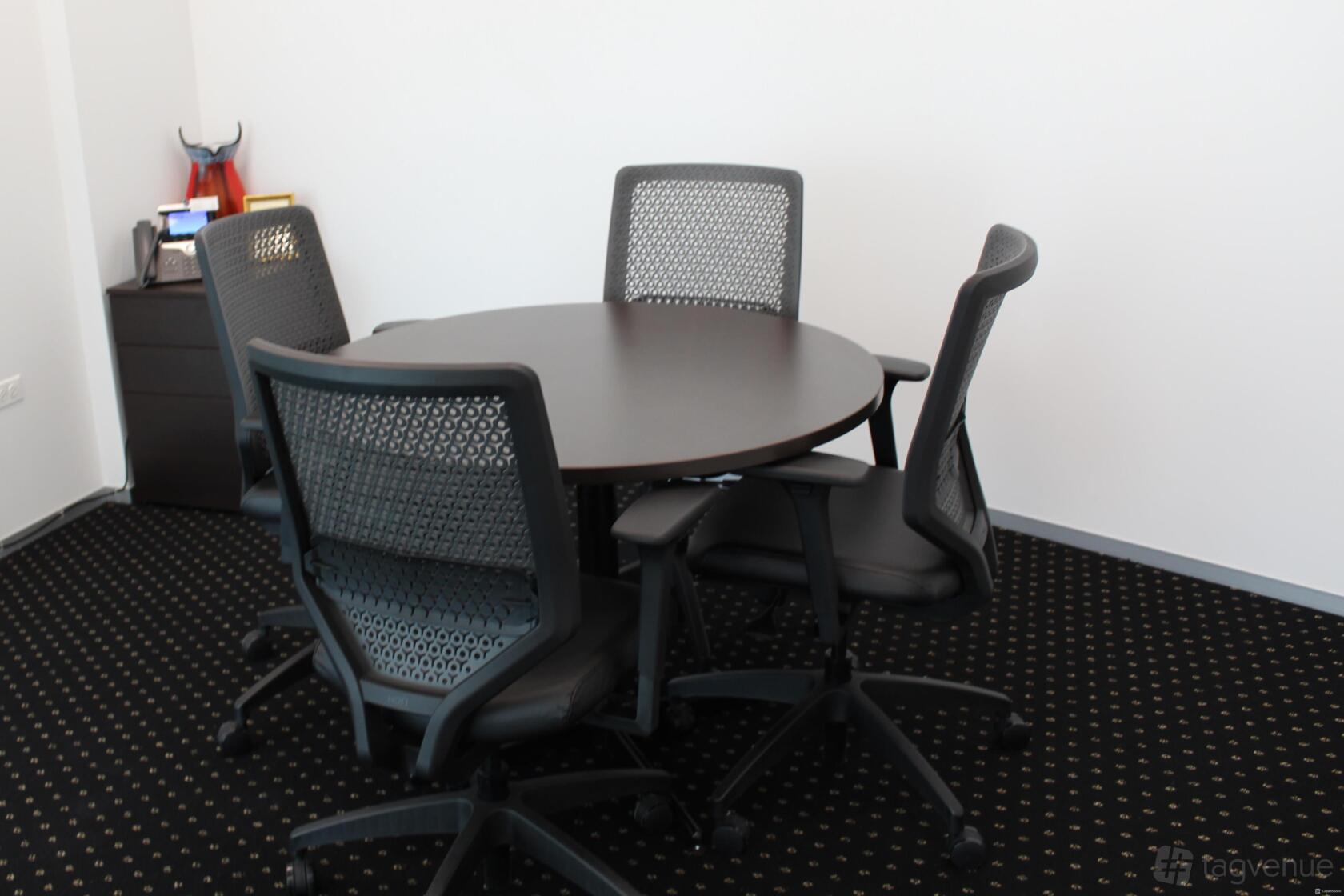 A meeting room with a round table, four mesh office chairs, and a small cabinet at Servcorp - River Point, West Loop, Chicago.
