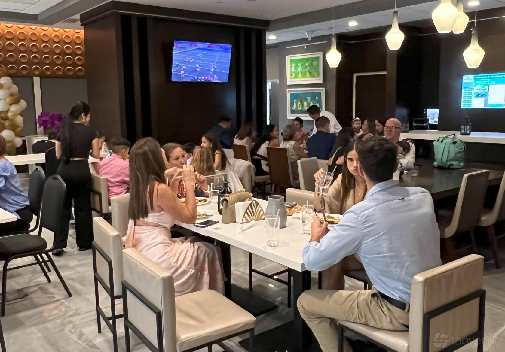 A restaurant with marble-topped tables, modern pendant lights, and wall art at Tabbouleh Grill.