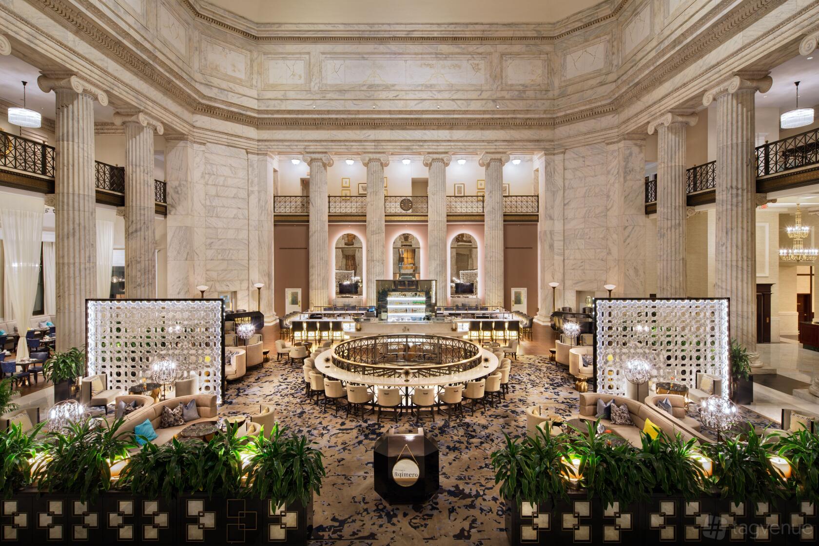 A restaurant lounge with marble columns, high ceilings, elegant sofas, and decorative screens at Aqimero.