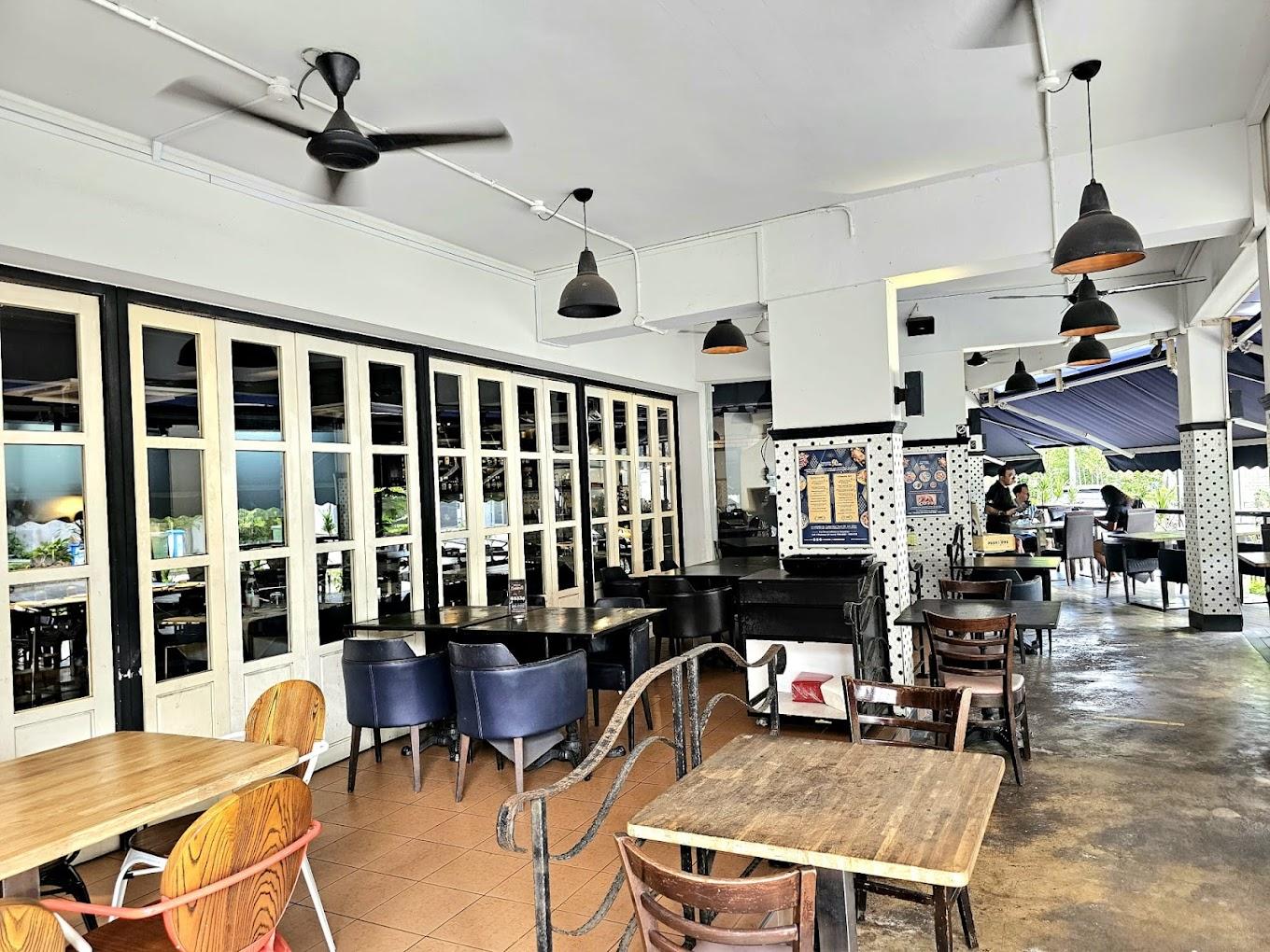 A restaurant with wooden tables, mixed seating, ceiling fans, and large folding glass doors at R Italian Kitchen & Smokehouse.