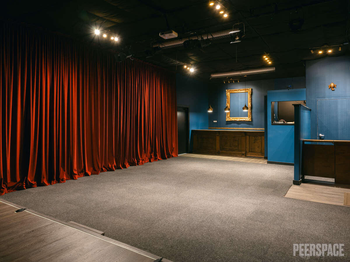 An event space in a theatre with red stage curtains, dark blue walls, and a vintage bar at The Coronation Theater and Events.