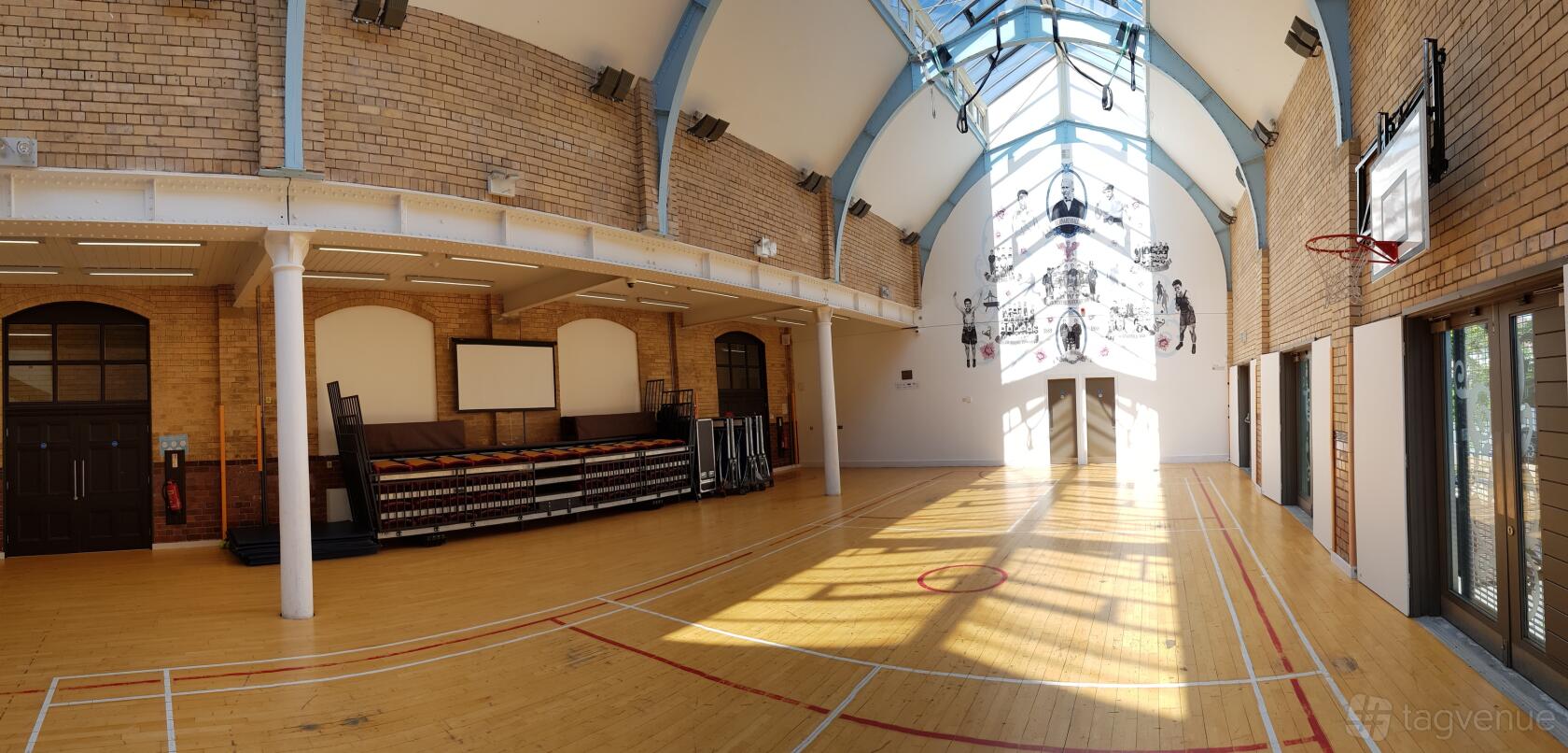 An event space with a vaulted ceiling, exposed brick walls, and skylights in The Florrie’s Victorian Gymnasium.