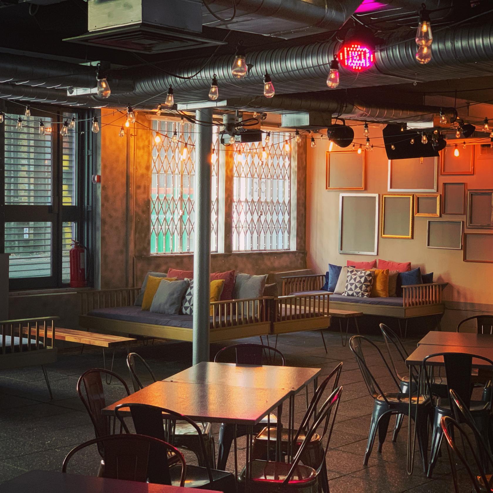 An event space with industrial lighting, empty picture frames on the wall, and cushioned bench seating at The Event Rooms.