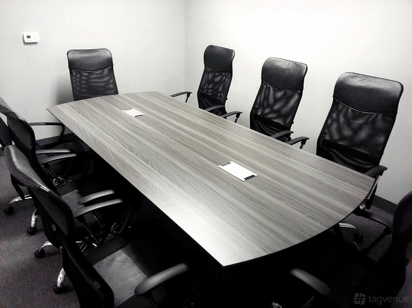A meeting room with a long wooden table, black leather chairs, and notepads at Sunset Meeting Space.