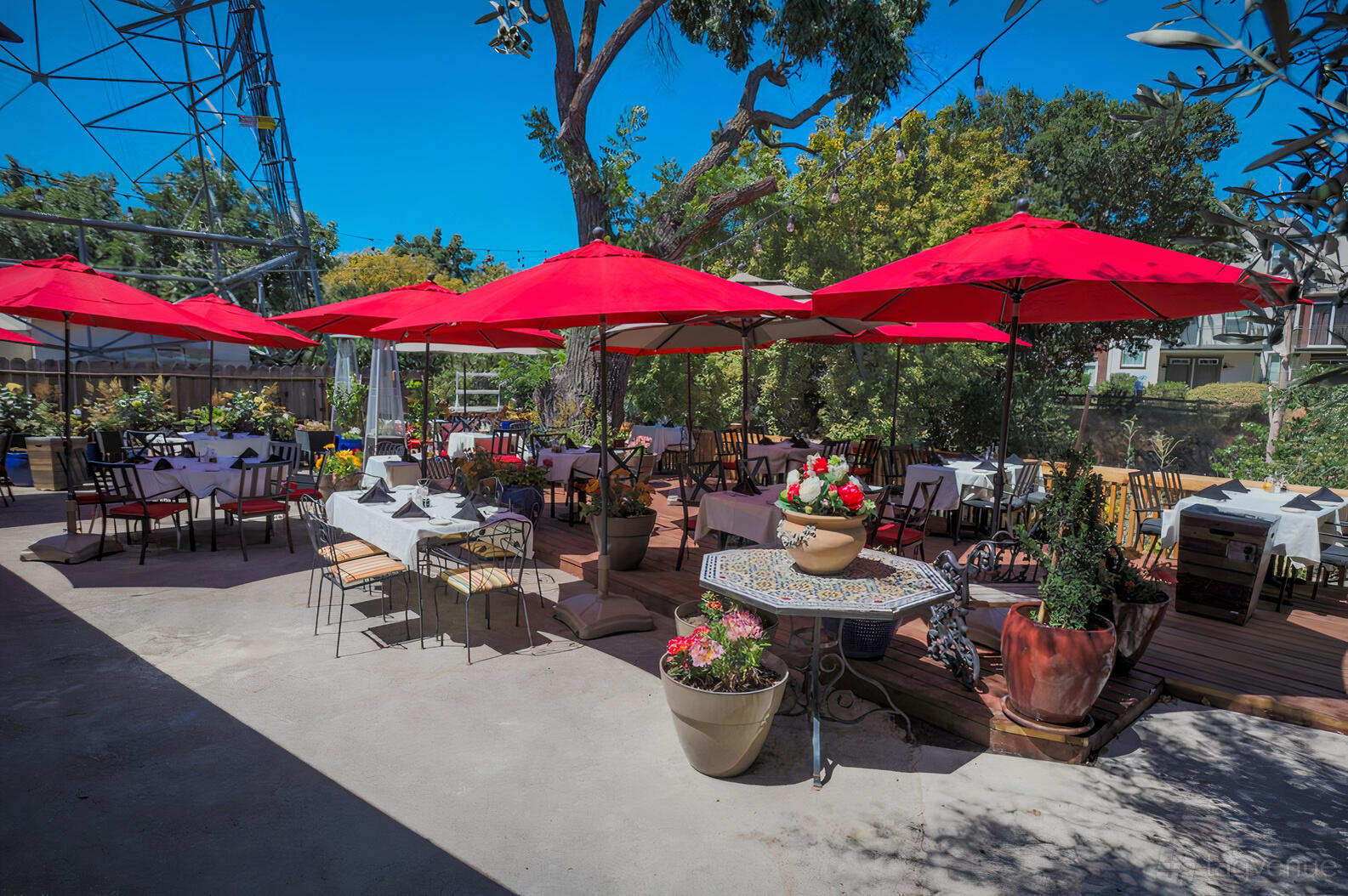 A terrace with red umbrellas, potted plants, and outdoor dining tables at Palermo Italian Restaurant.