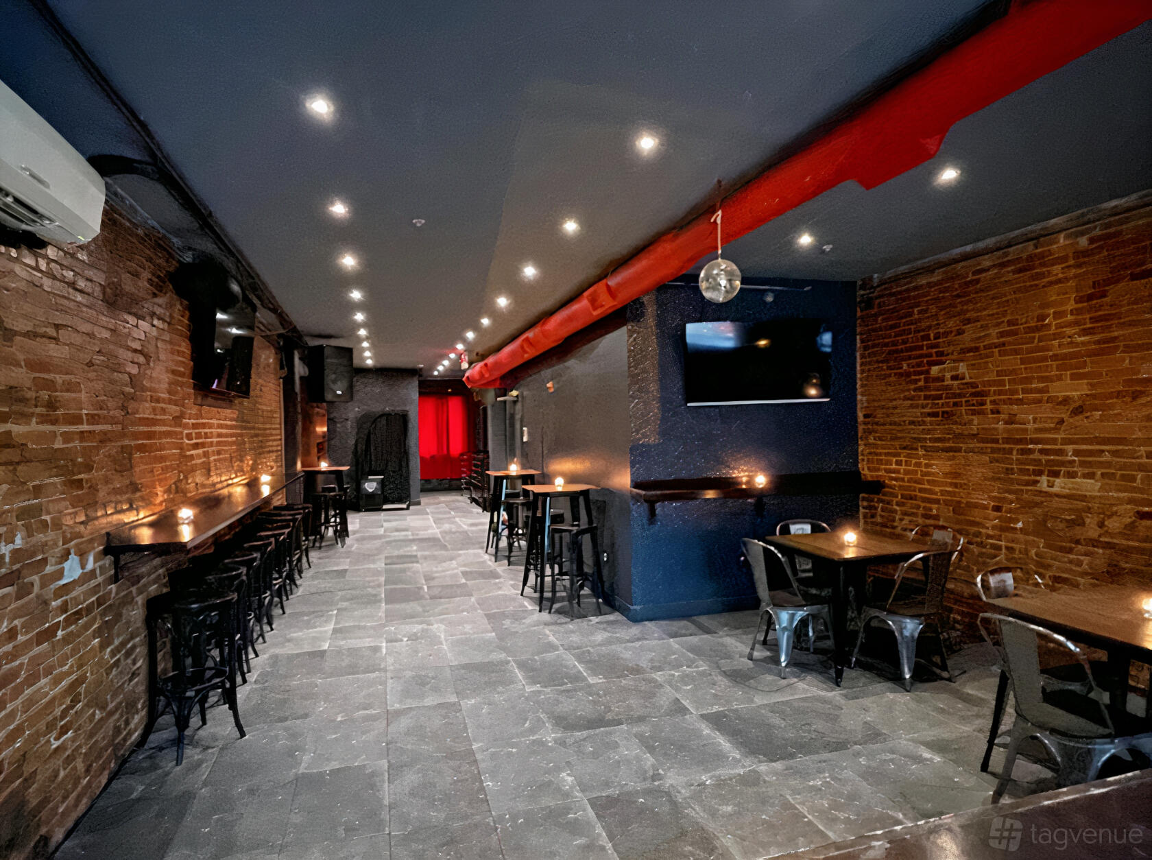 A function room with exposed brick walls, black metal chairs, and a mounted TV at Clubhouse at Sudhouse DC.