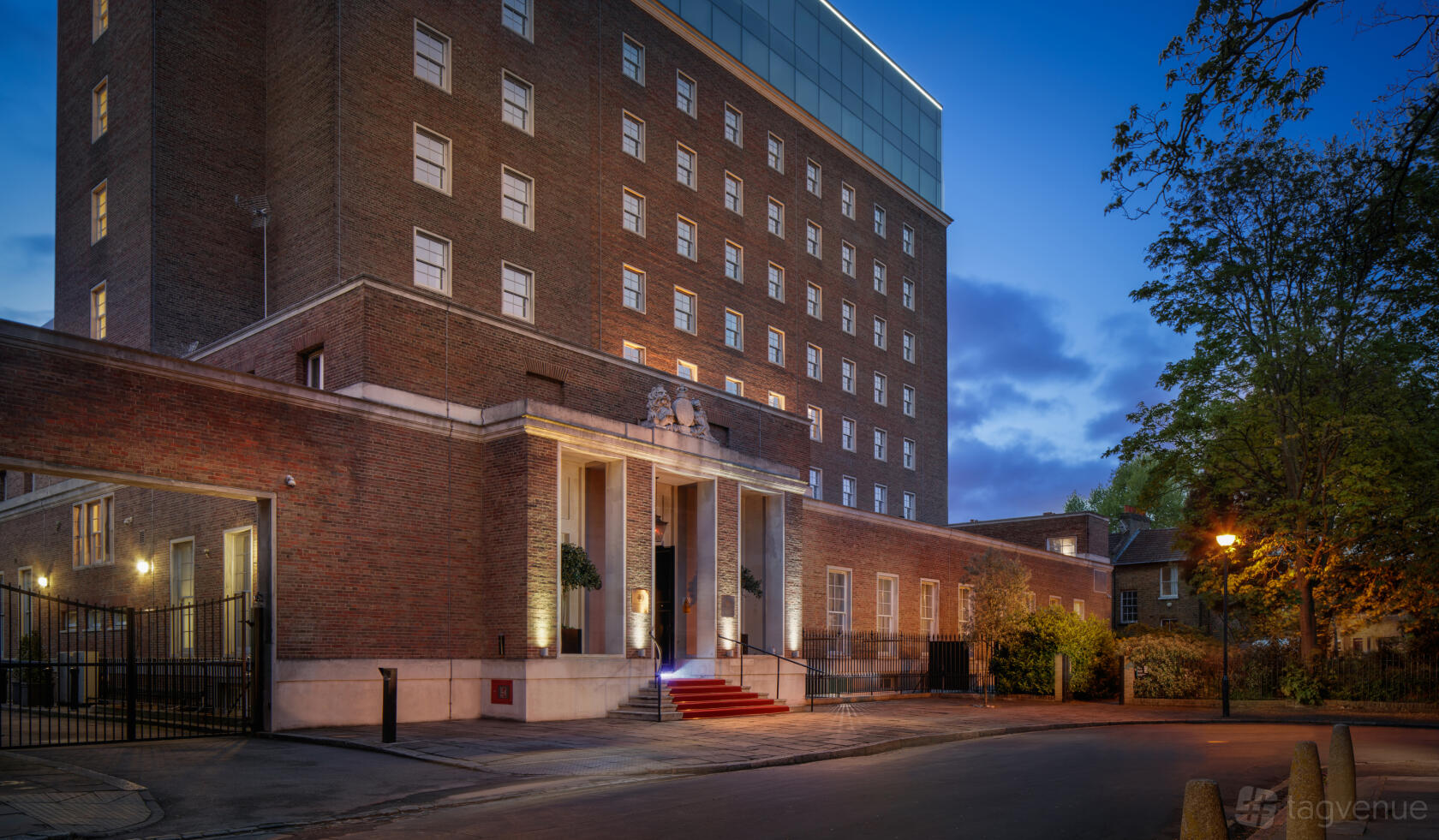 A hotel exterior with red brick facade, columned entrance, and red carpet at DoubleTree by Hilton London Greenwich.