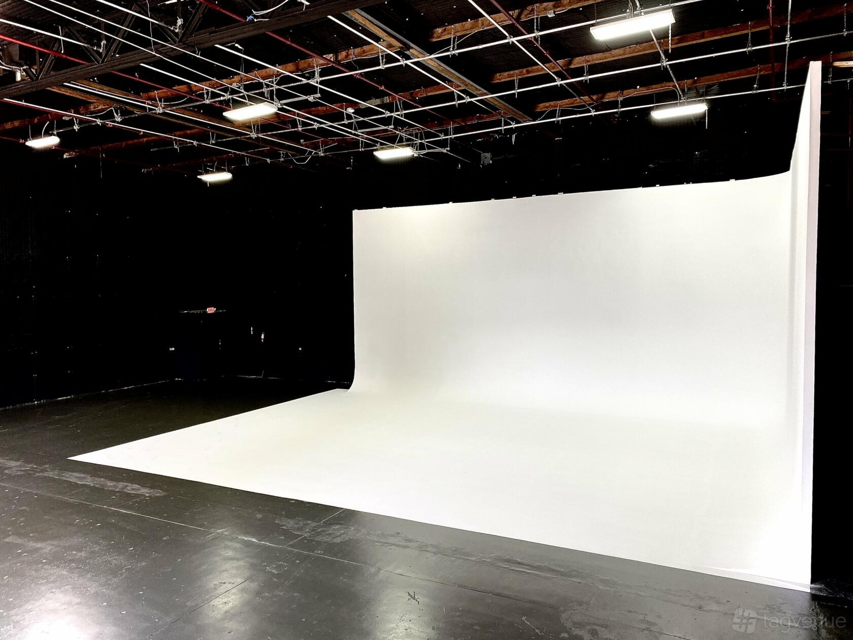 A photo studio with a large white cyclorama wall and overhead grid lighting at East End Studios.