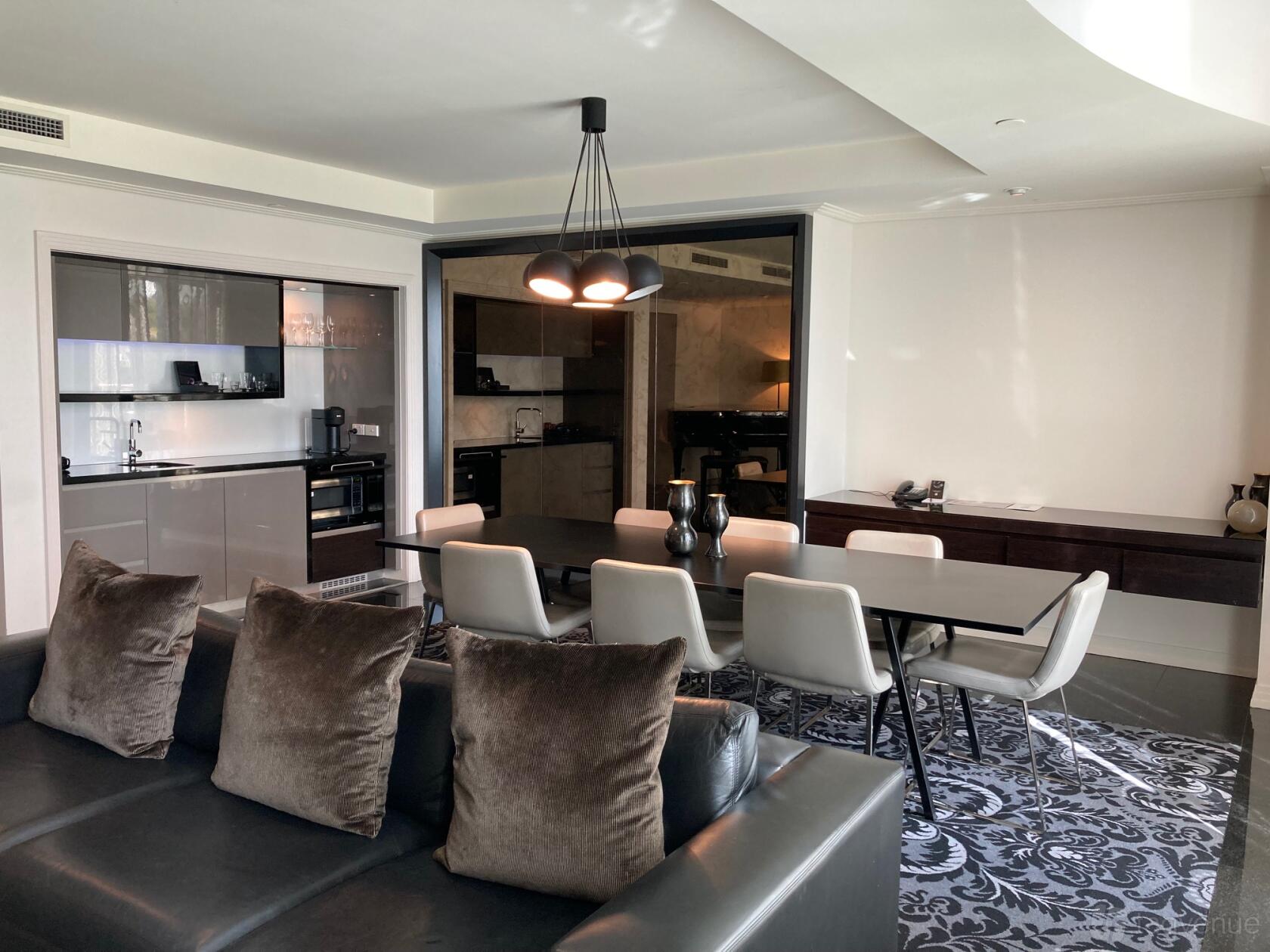 A hotel suite with a dining table, modern kitchenette, and pendant lighting at The Como Melbourne.