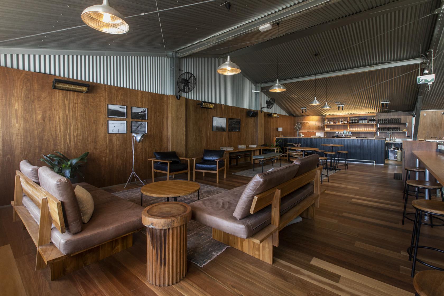 An event space in a restaurant with wooden floors, lounge seating, and a bar at Three Blue Ducks Melbourne.