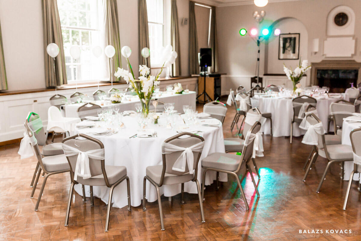 An event venue with parquet floors, round tables with white linens, and large windows at Goodenough House.