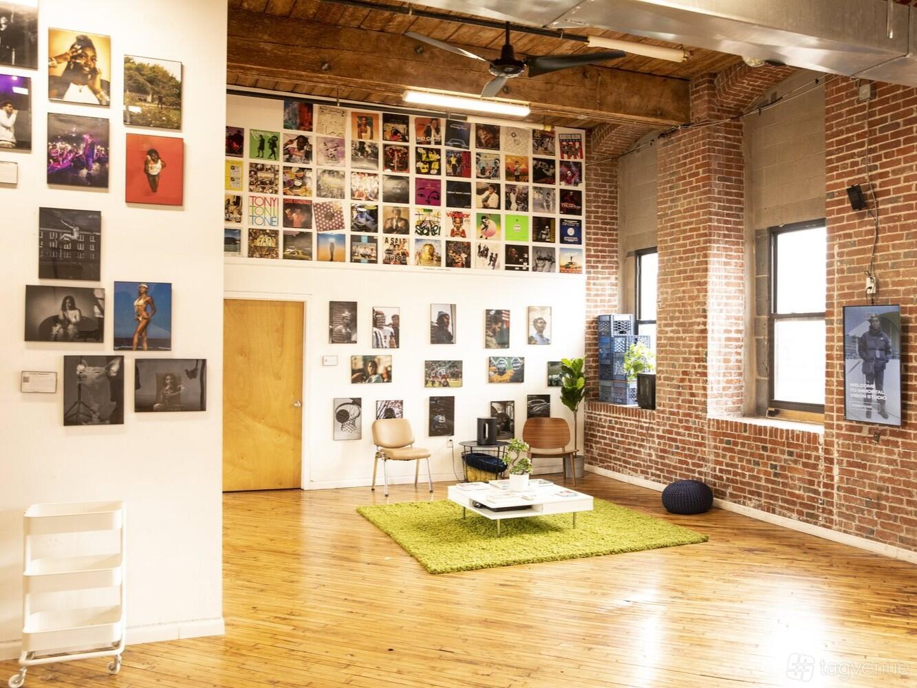An event venue with exposed brick walls, gallery-style photo displays, and hardwood floors at Immortal Vision Studio.