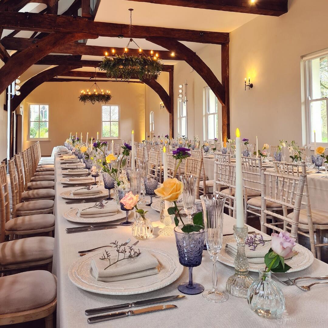 A castle meeting room with long banquet tables, wooden beams, and floral centerpieces at Ashridge House.