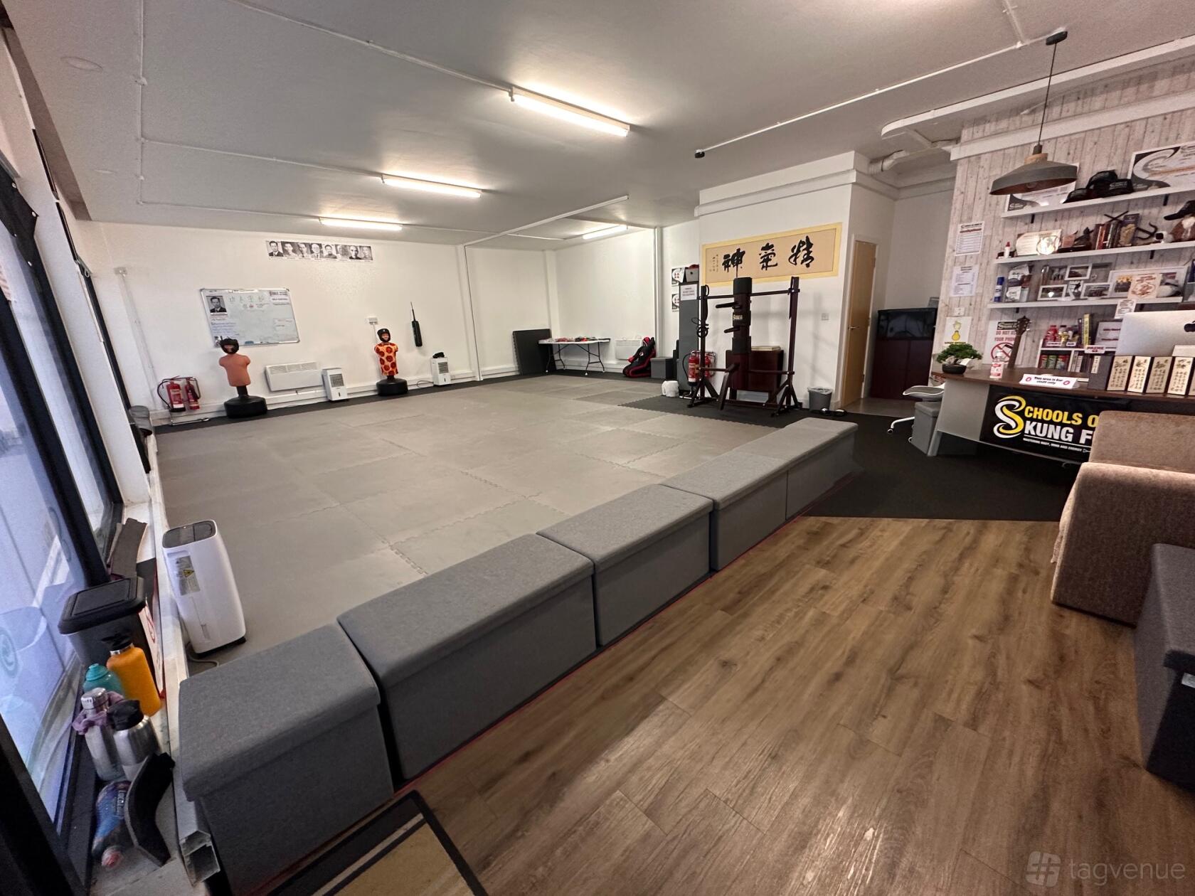 A martial arts training hall with padded floors, mirrored walls, and seating benches at Redhill Martial Arts.