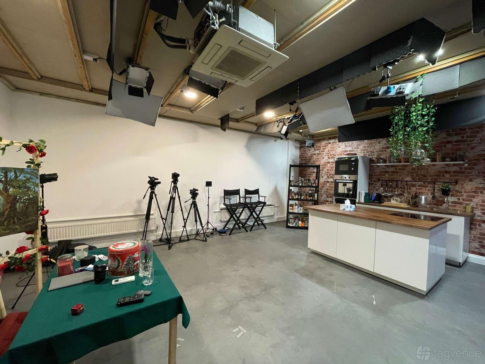 A photo and film studio with lighting equipment, tripods, exposed brick walls, and a kitchenette at Watlling Studio.