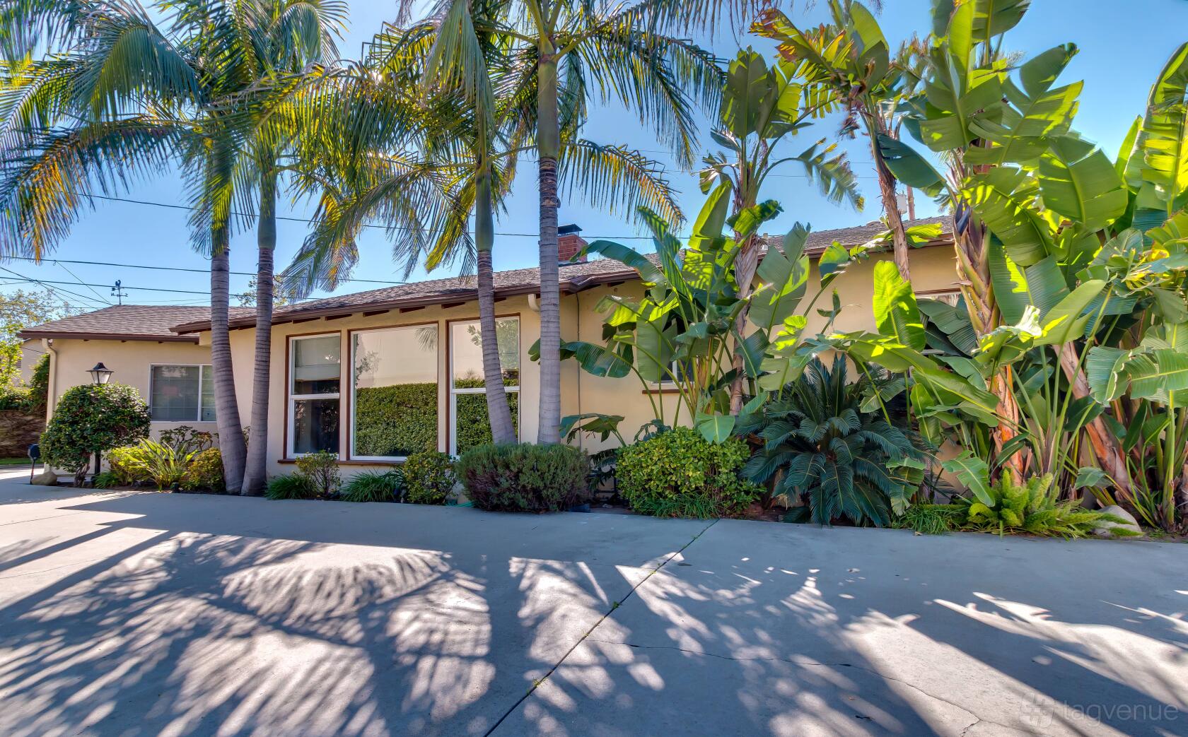 A film and photo studio with a beige exterior, large front windows, and palm trees at Beautiful Unique Burbank house.
