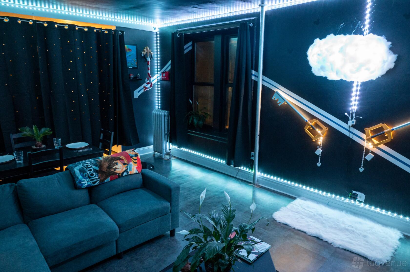 An event venue with a themed mural, string lights, blue sectional sofa, and decorative pillows at Kingdom Hearts NYC.
