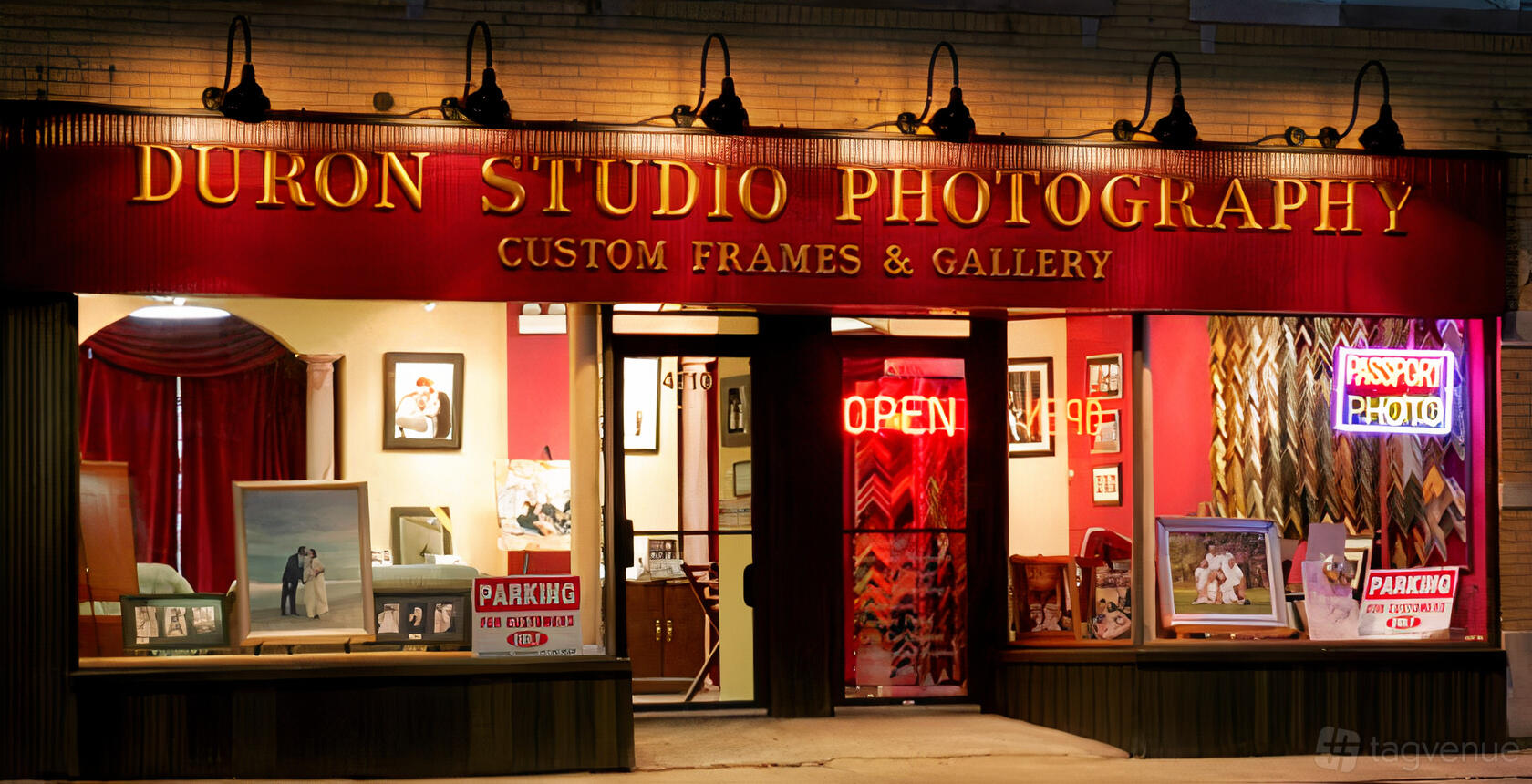 A film and photo studio with illuminated red signage, framed artwork displayed in the windows at Duron Studio Photography.