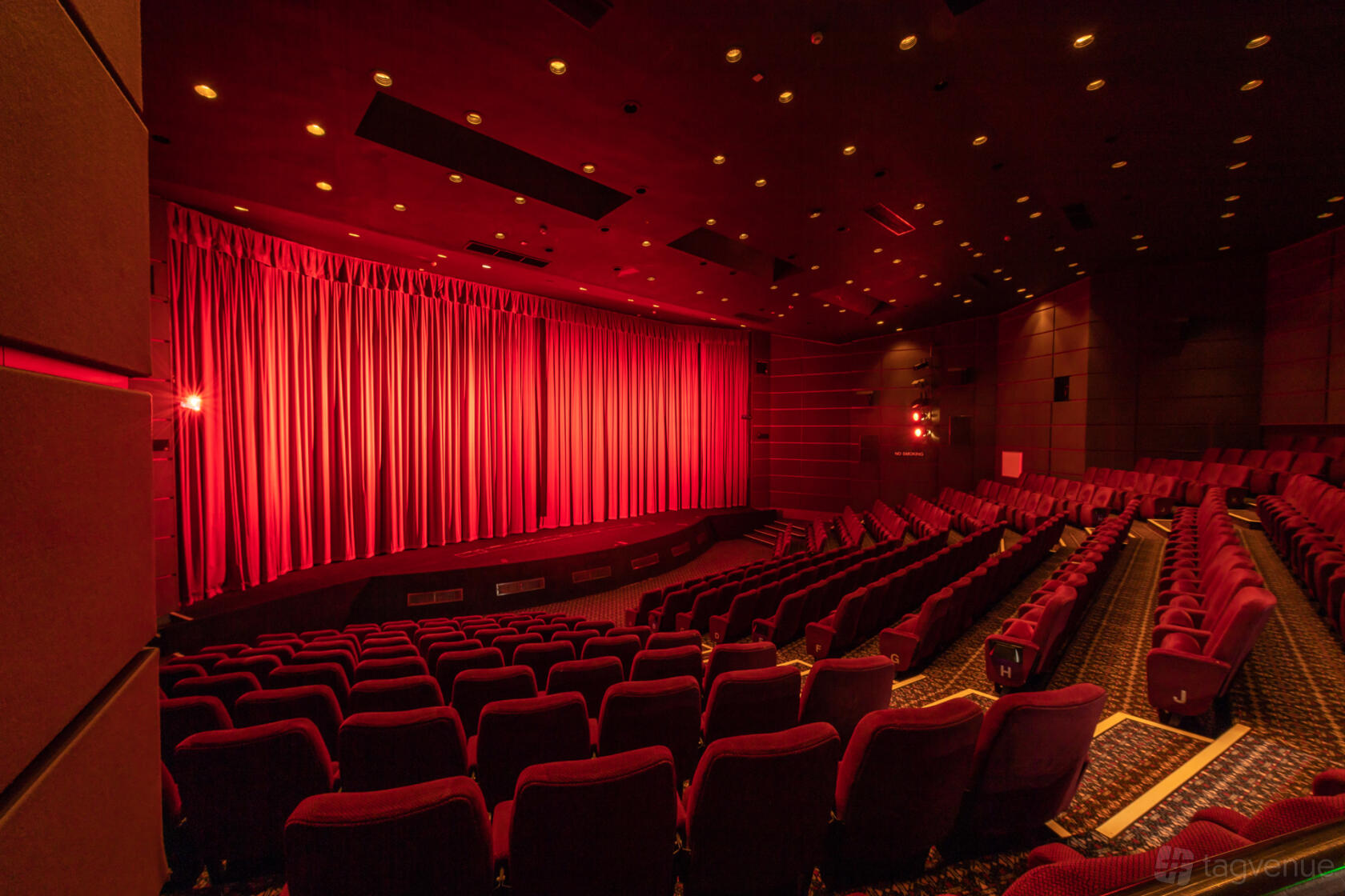 A museum auditorium with red reclining seats and a stage framed by red curtains at The National Science and Media Museum.